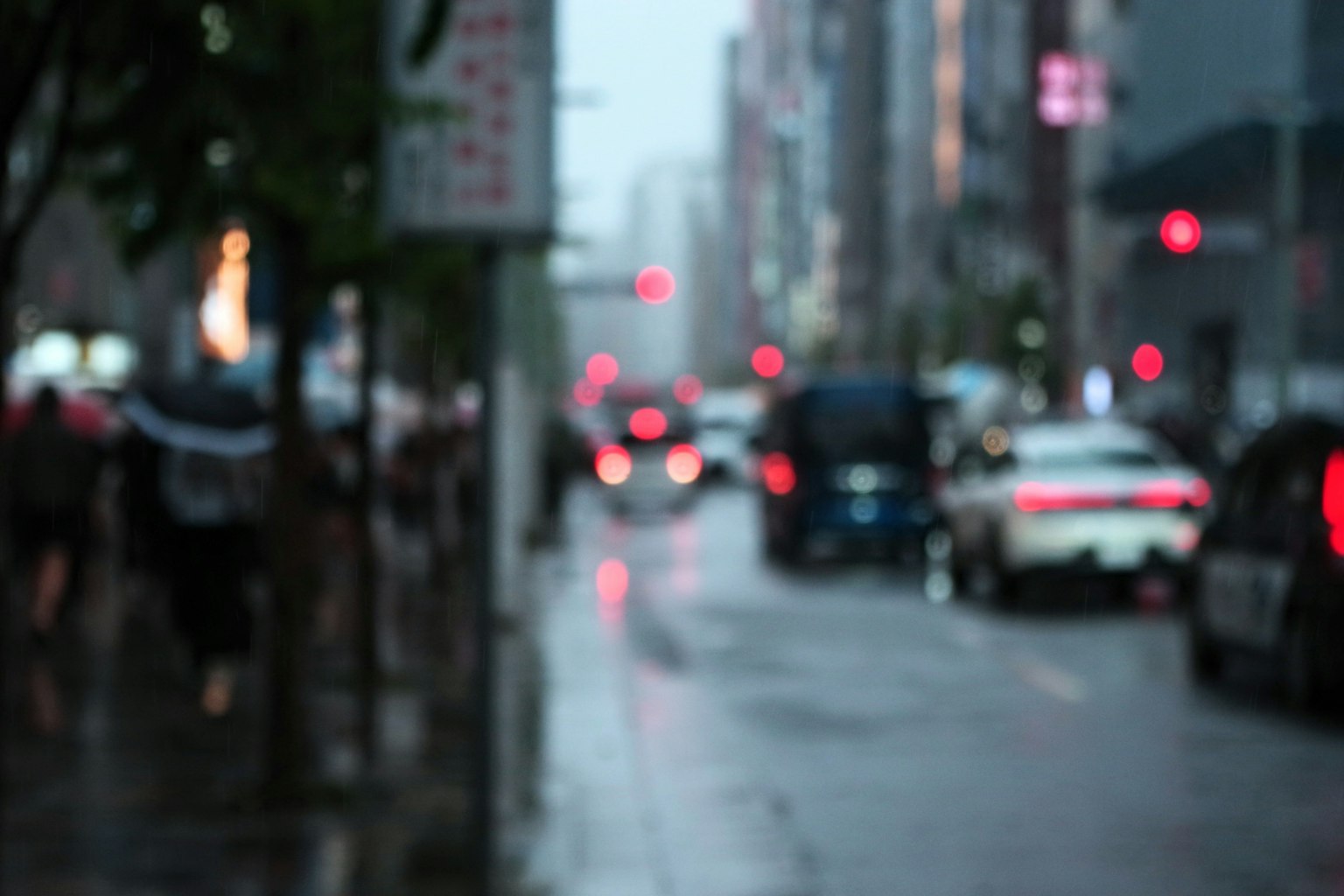 模糊的城市景觀在雨中與汽車和行人
