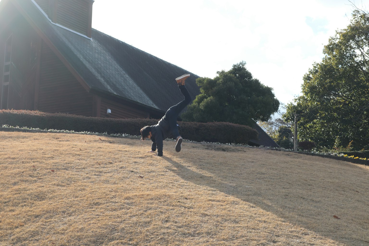 A person doing a handstand on grass with a church building in the background