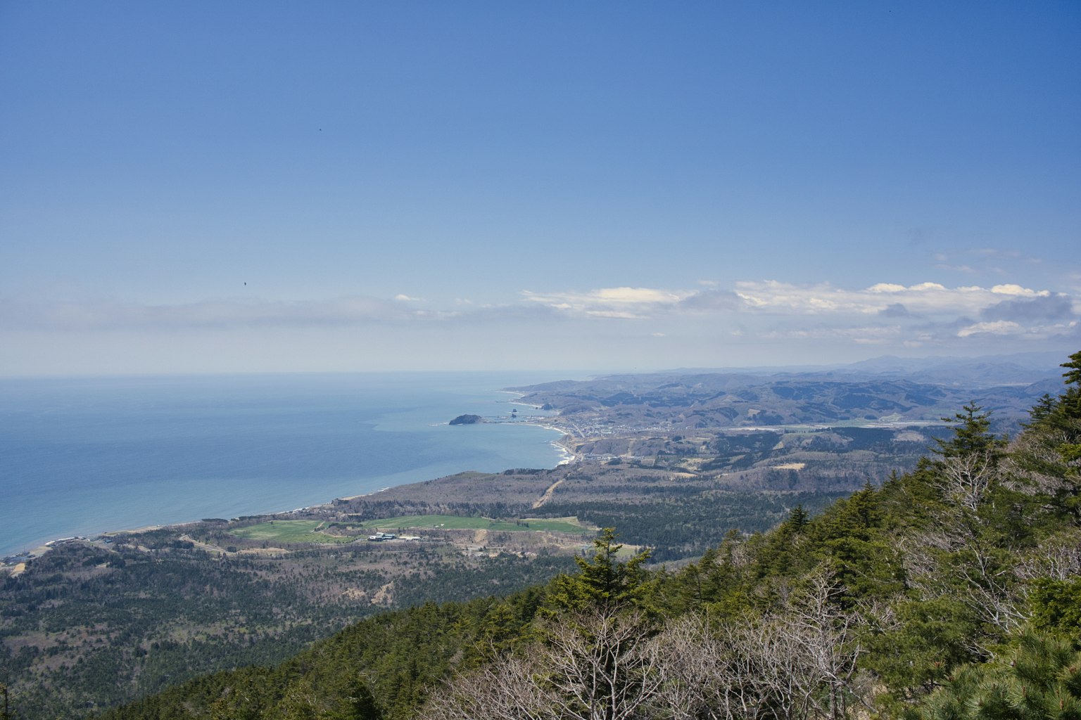 Küstenlandschaft mit Bergen und Ozean unter einem klaren blauen Himmel