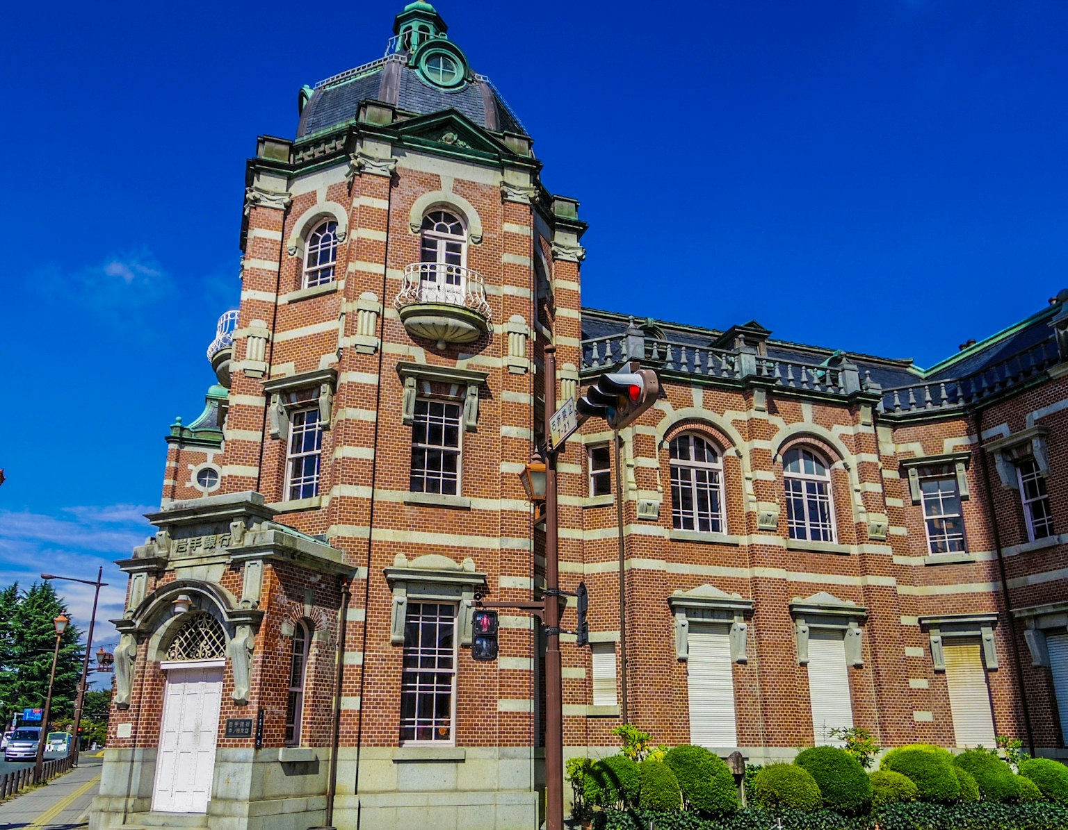 Edificio histórico de ladrillo rojo con cúpula verde y cielo azul