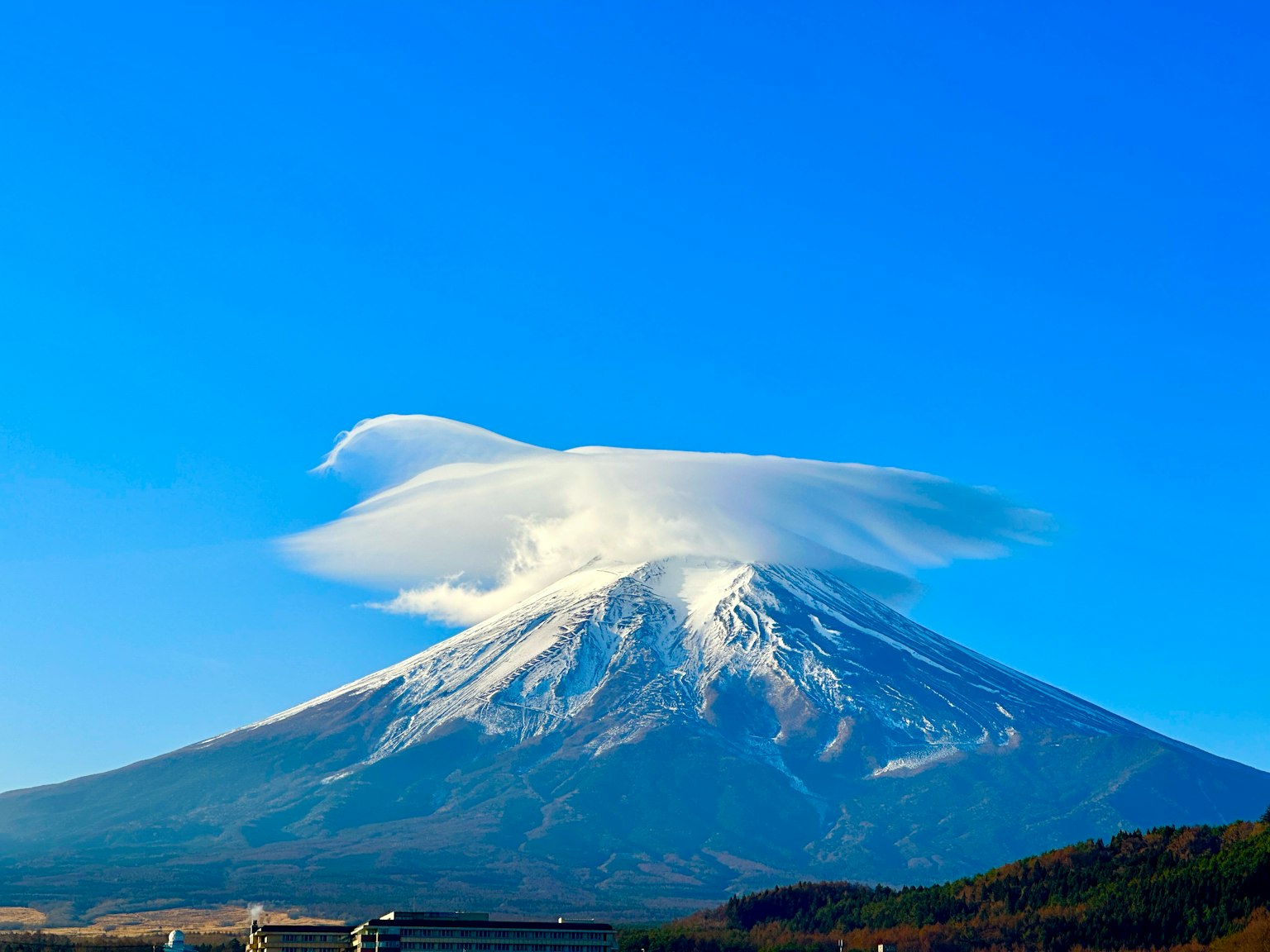 Monte Fuji con una nuvola in cima sotto un cielo blu chiaro