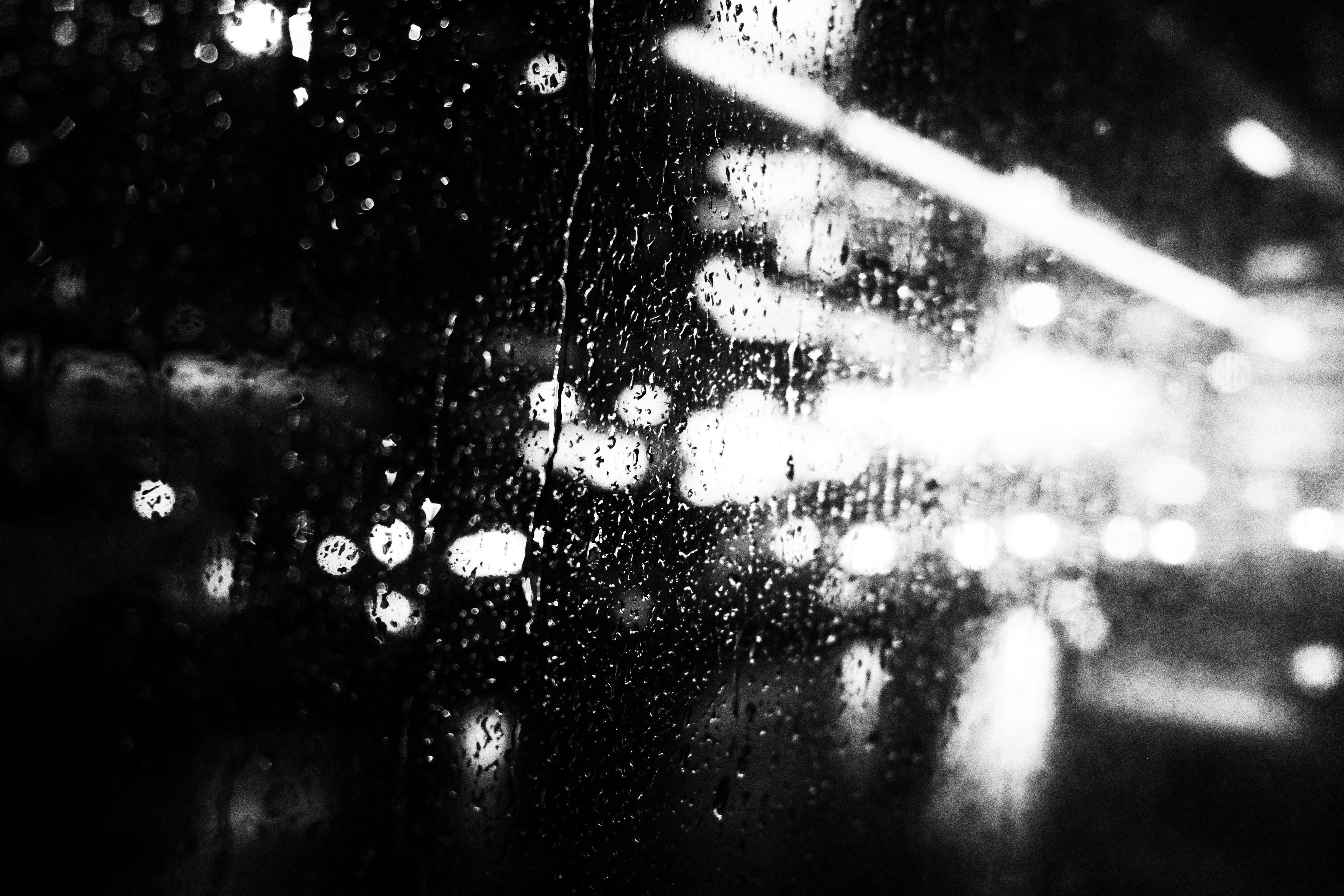 雨粒が窓に付いた夜の車道のにぎわい