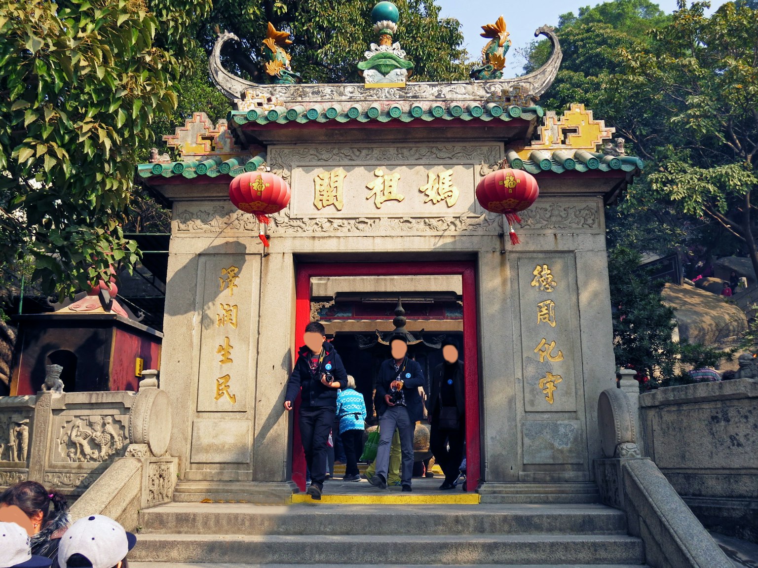 Ingresso di un tempio tradizionale con persone in piedi lanterne rosse e decorazione del tetto ornata