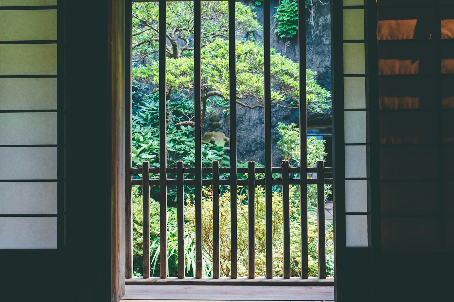 View of a lush garden through a wooden lattice window