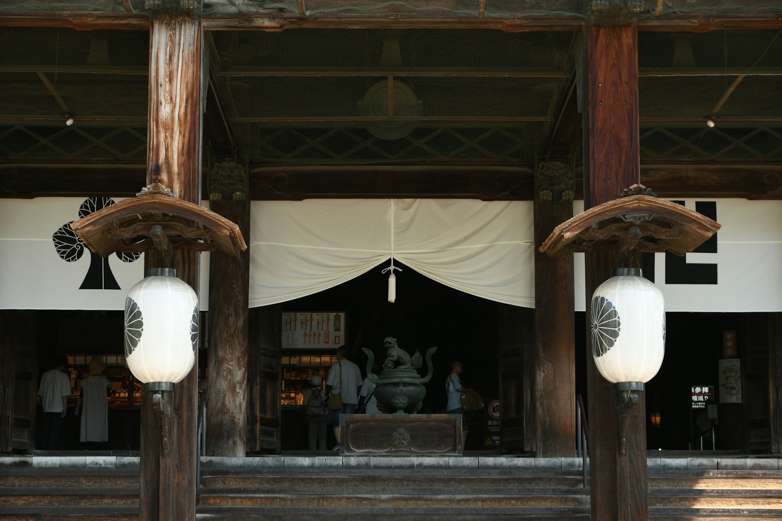 Traditional Japanese building with wooden pillars and lanterns in the foreground