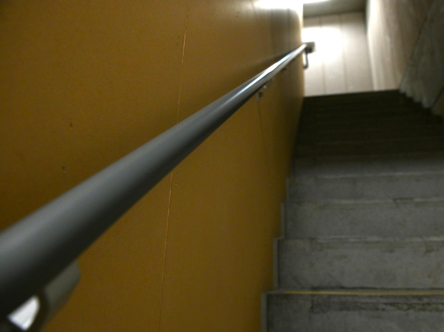 Escalera oscura con pasamanos negro y escalones de concreto