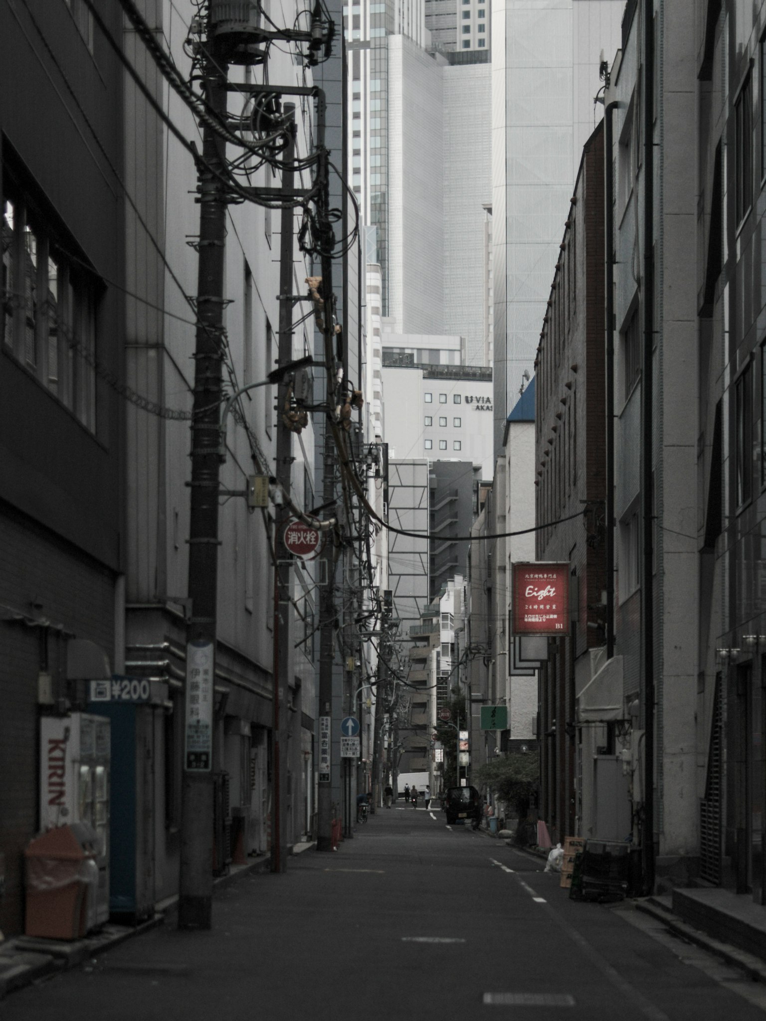 Callejón estrecho rodeado de edificios grises con cables eléctricos enredados