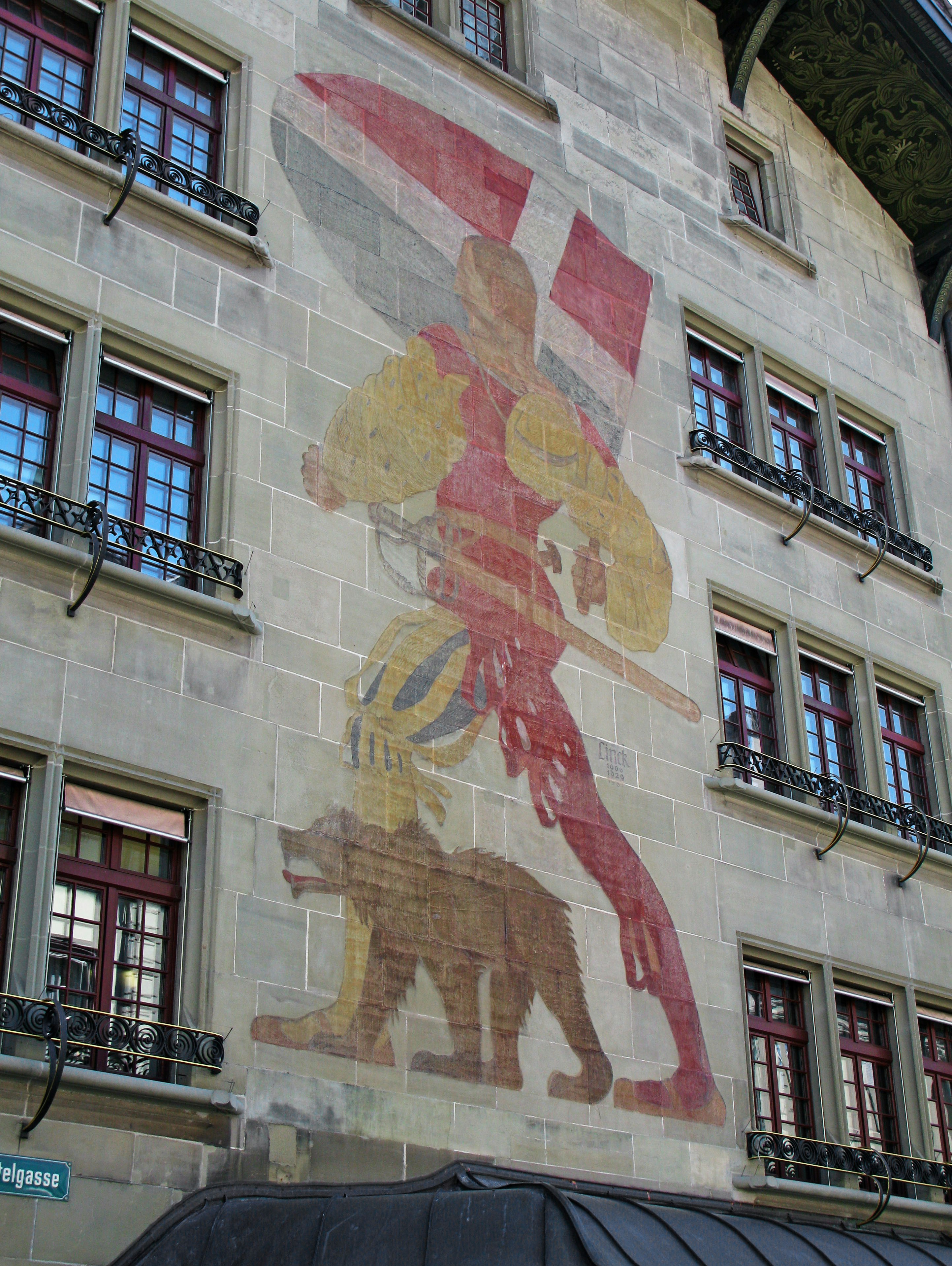 grande murale di una figura su un muro di un edificio con finestre