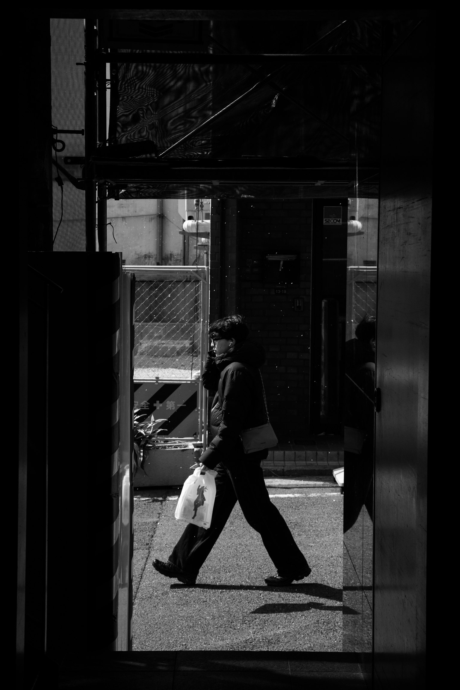 Silhouette de una persona caminando con una bolsa en un paisaje urbano en blanco y negro de alto contraste