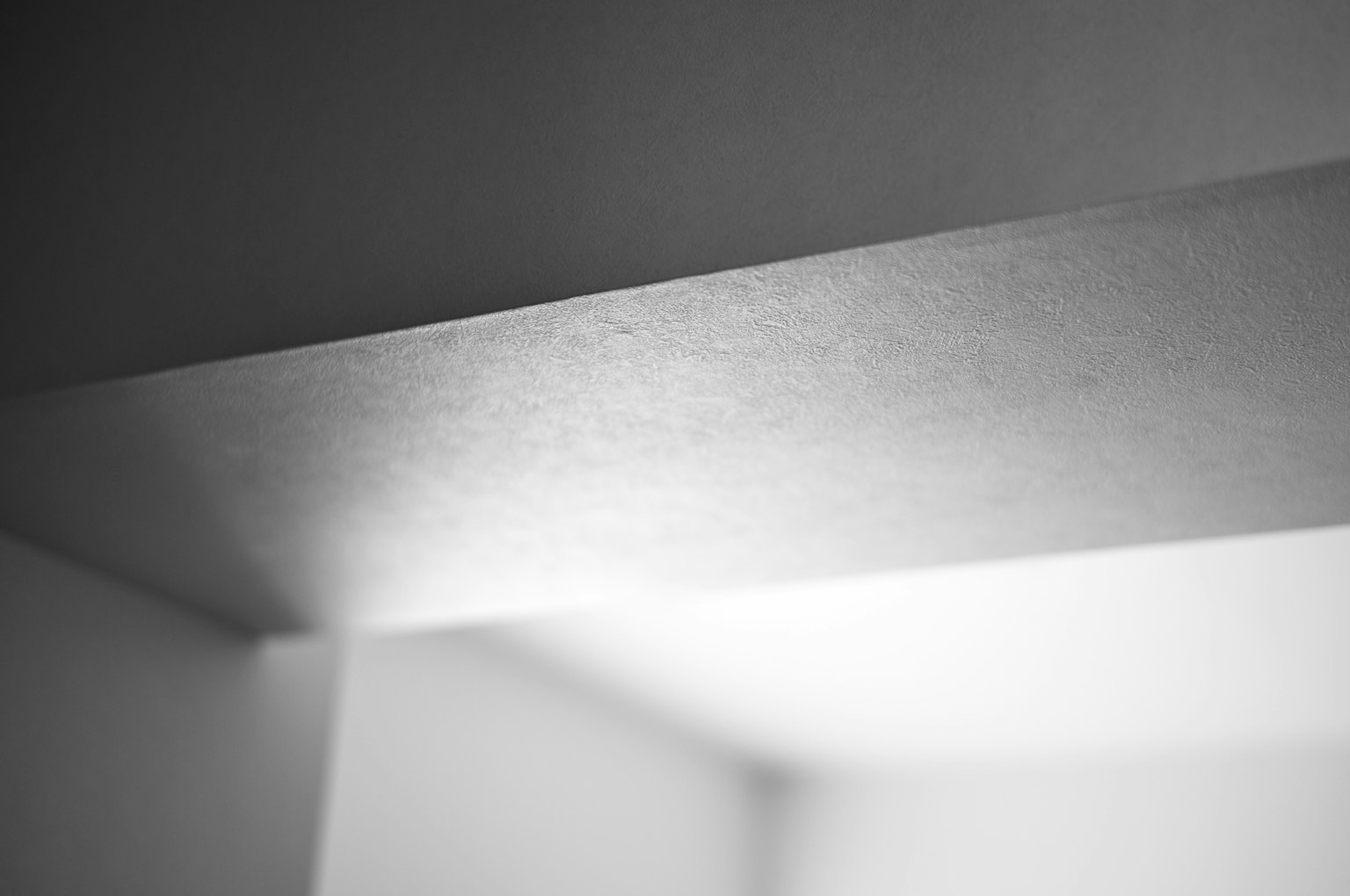 Abstraktes Schwarz-Weiß-Bild einer Wand-Ecke mit Lichtreflexion
