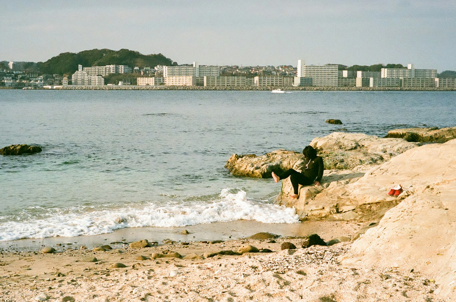 在海岸上浸泡腳的人，背景是城市景觀