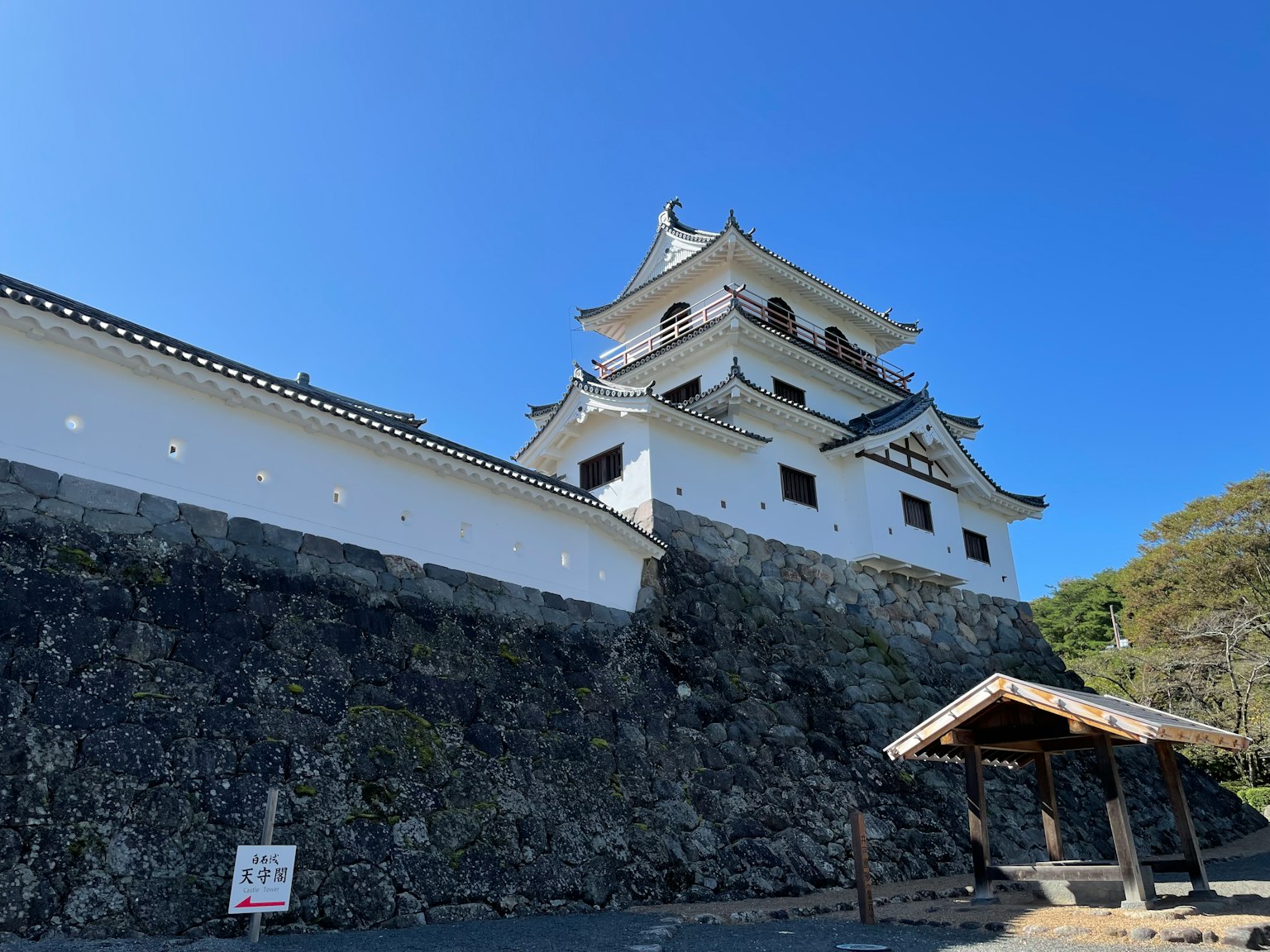 Japanisches Schloss mit weißen Wänden und Steinfundament unter einem klaren blauen Himmel
