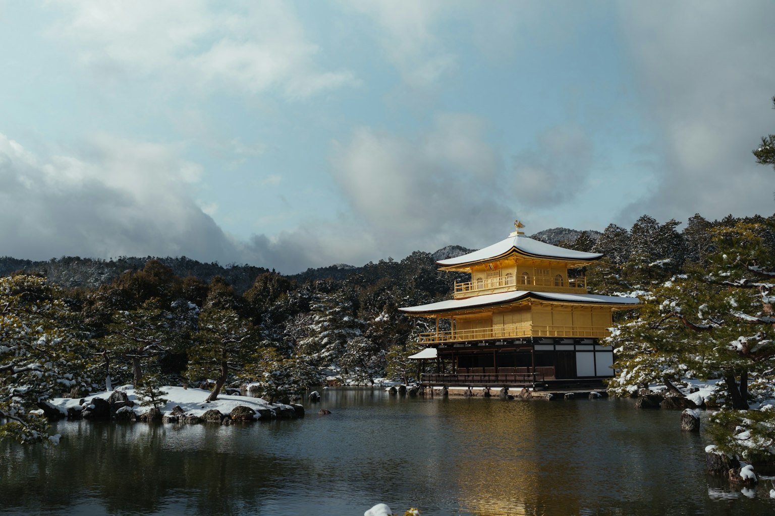 被雪覆蓋的金閣寺與寧靜的池塘