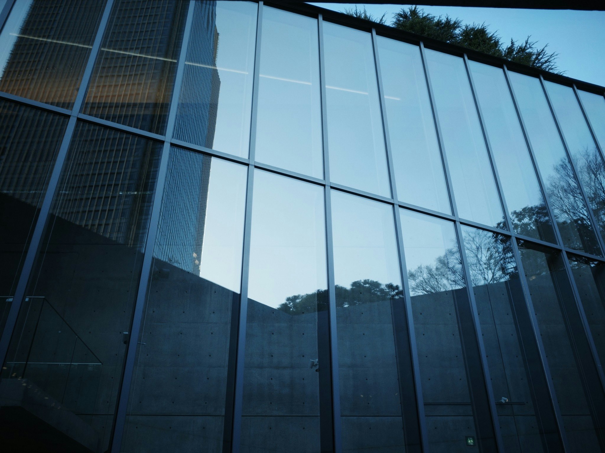 ガラスのファサードを持つ現代的な建物の反射が映る