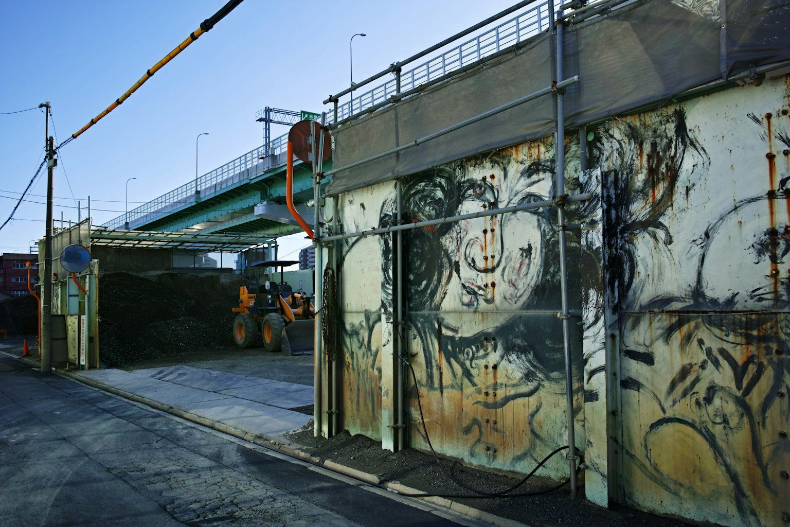 工事現場の壁に描かれたアートと近くの橋