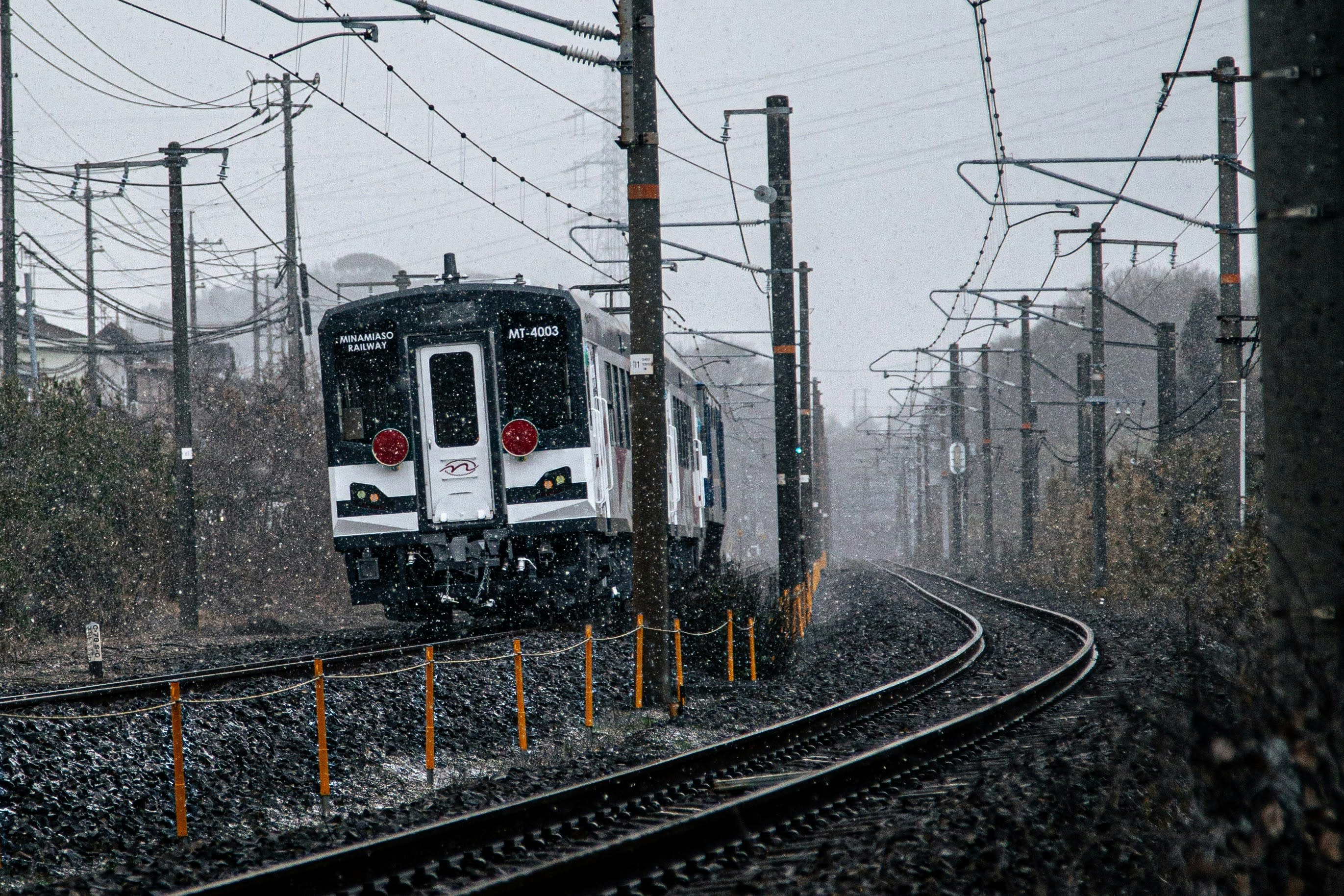 雪降りの南阿蘇鉄道を走る列車の前景