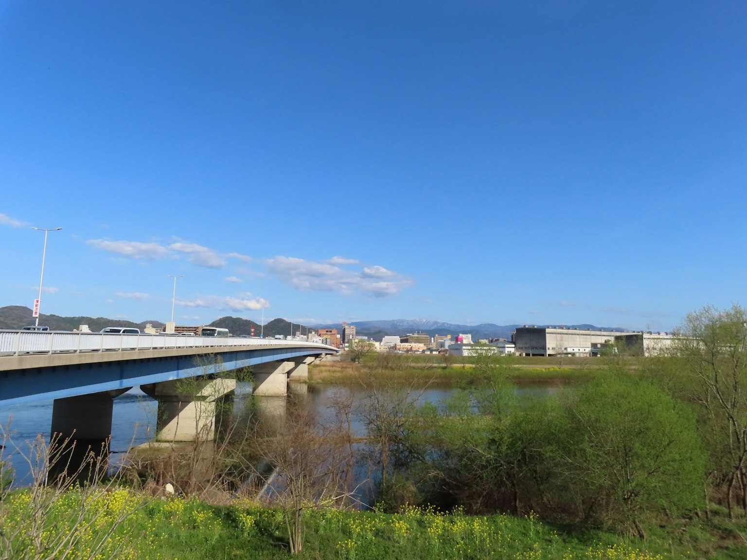 Scenic view of a river and bridge under a blue sky Green vegetation along the riverbank Calm water surface