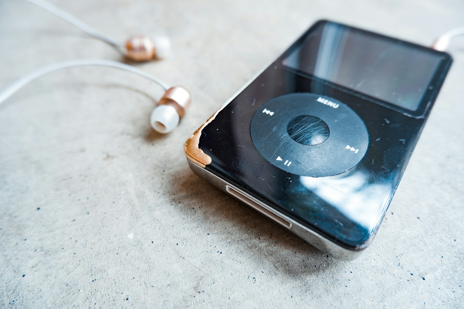 Un vecchio iPod con auricolari appoggiato su una superficie di cemento