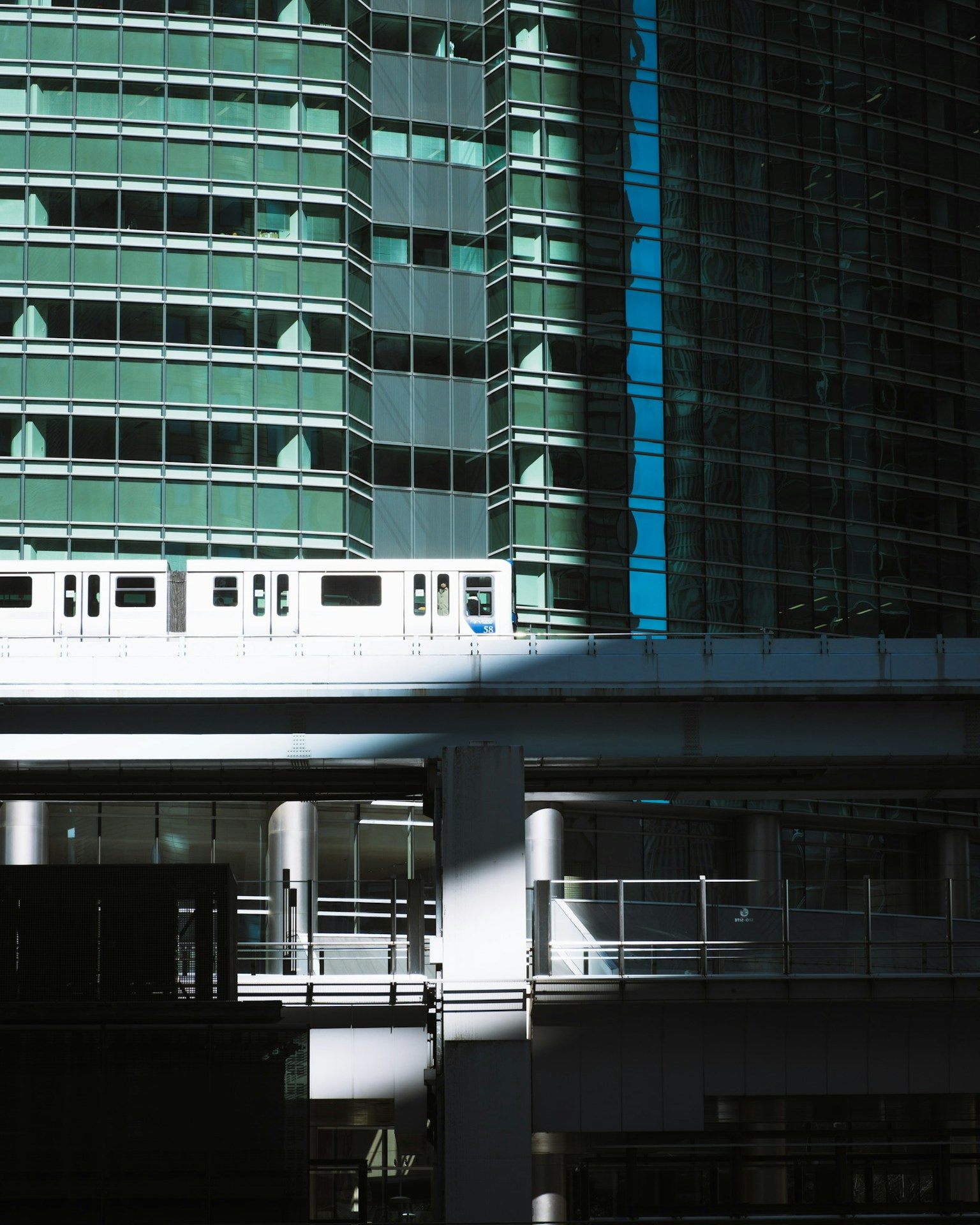 Tall blue glass skyscraper with a white train track below