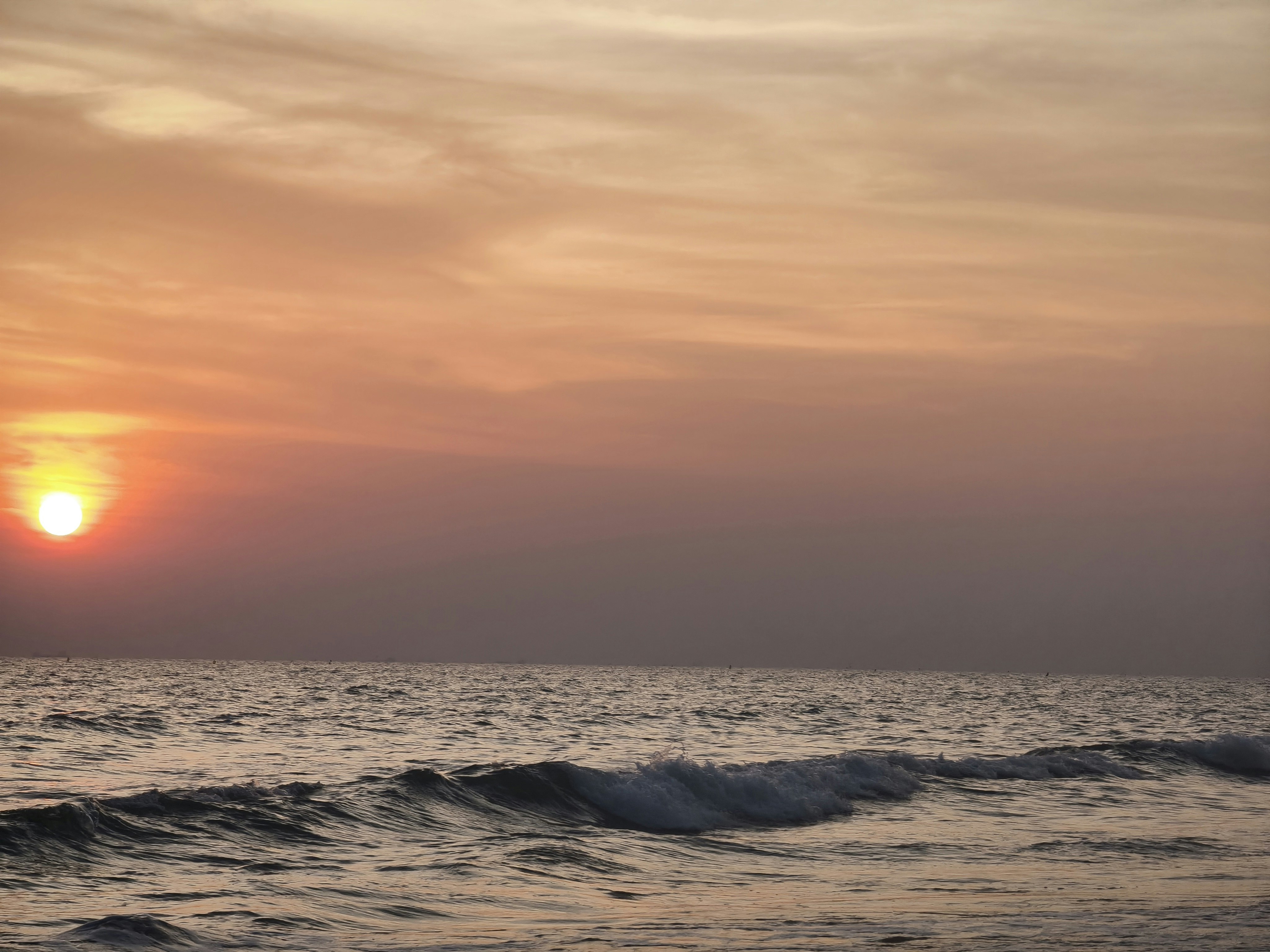 夕暮れの海面に打ち寄せる波と水平線の空