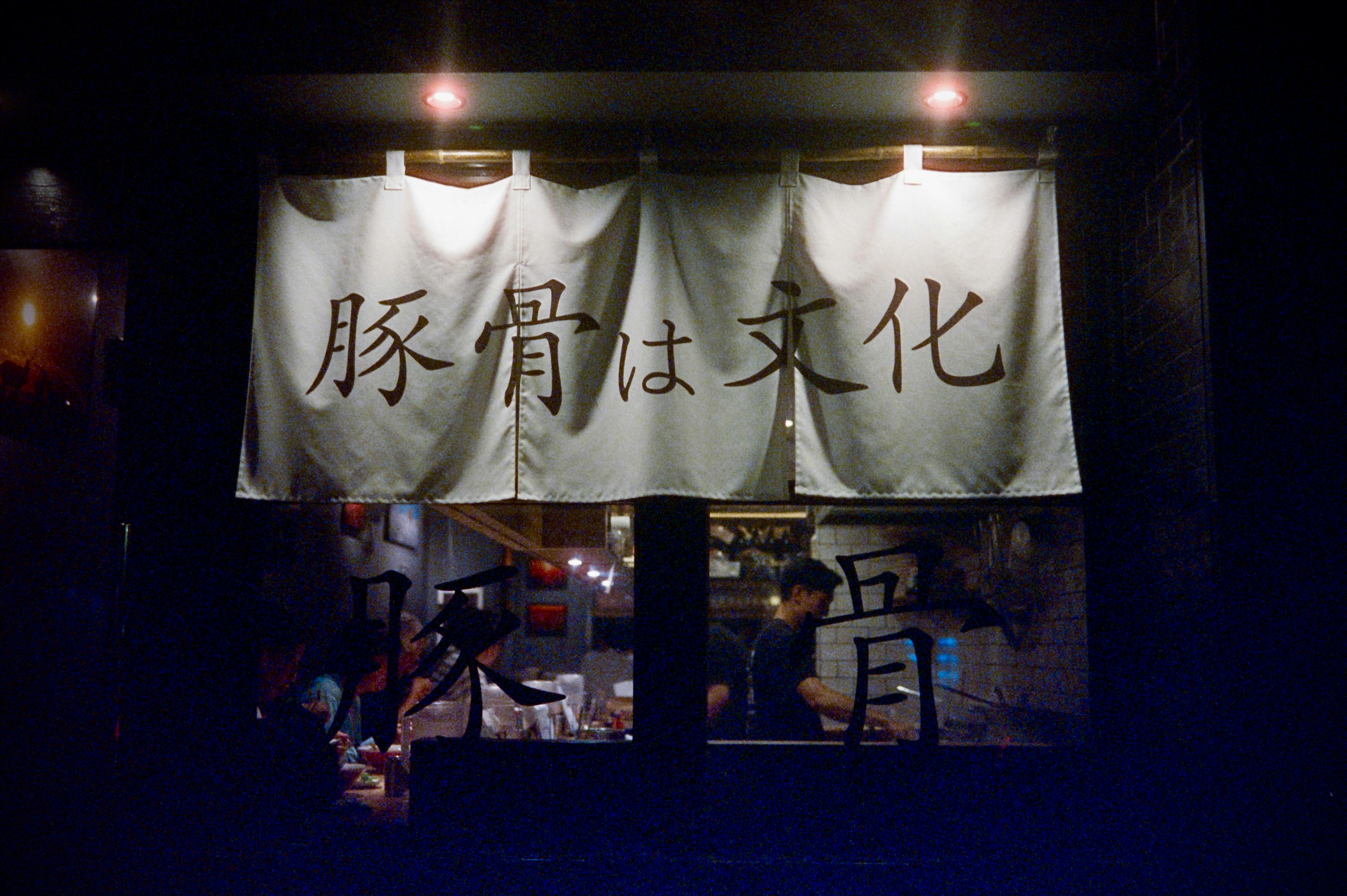 豚骨は文化と書かれた暖簾のある店内の夜景