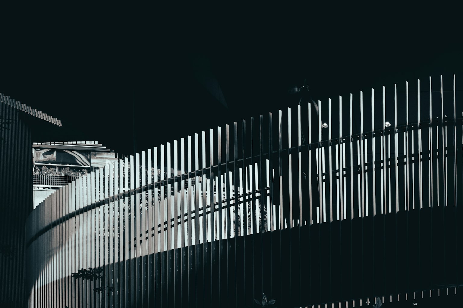 Image featuring a curved fence against a dark background