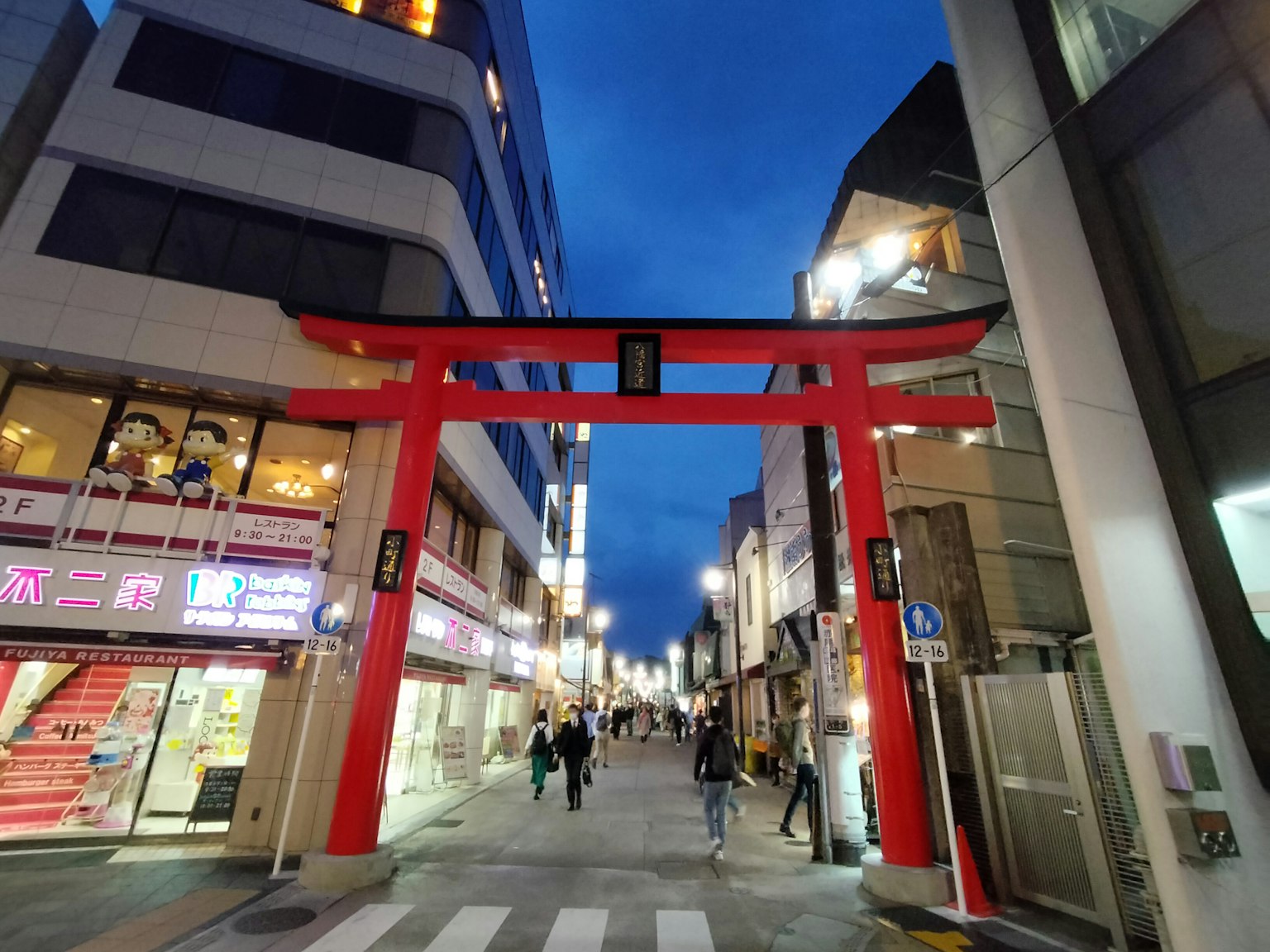 Puerta torii roja en una calle de la ciudad por la noche