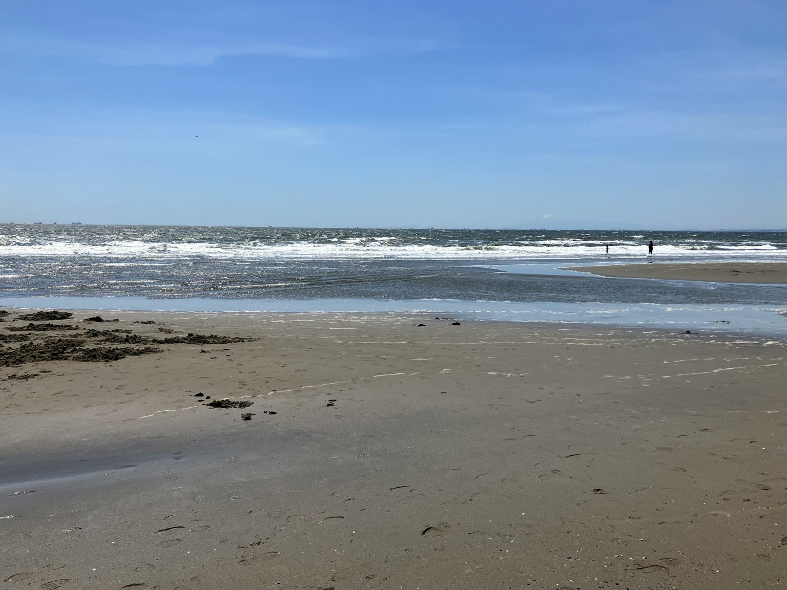 ฉากชายหาดที่มีคลื่นซัดและท้องฟ้าสีฟ้าสดใส