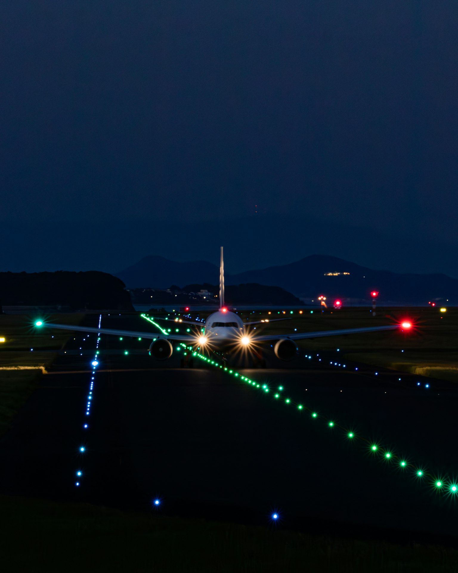 夜間在跑道上降落的飛機和多彩的跑道燈光