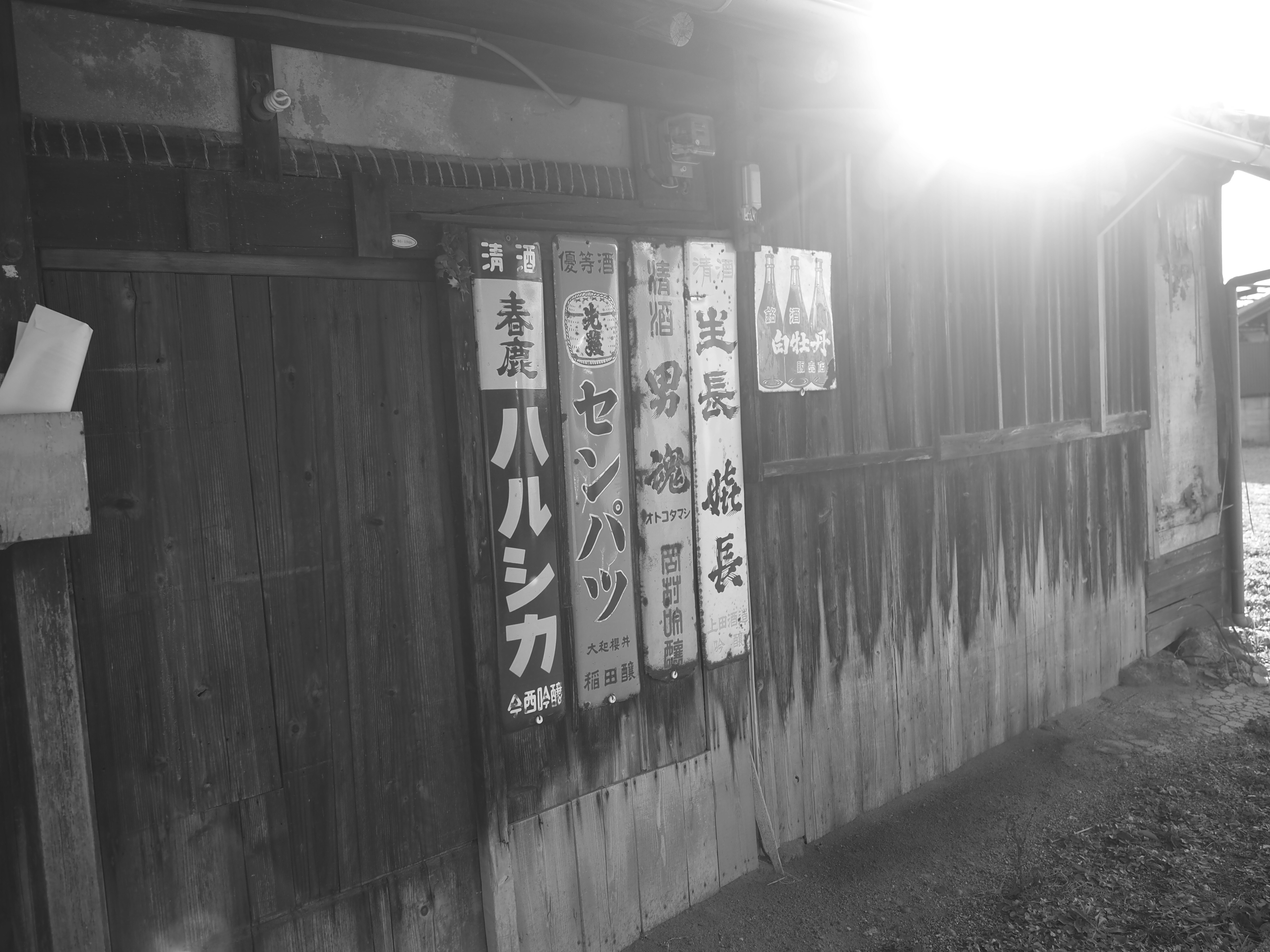 木の壁に並ぶ暖簾と看板のある路地の入口