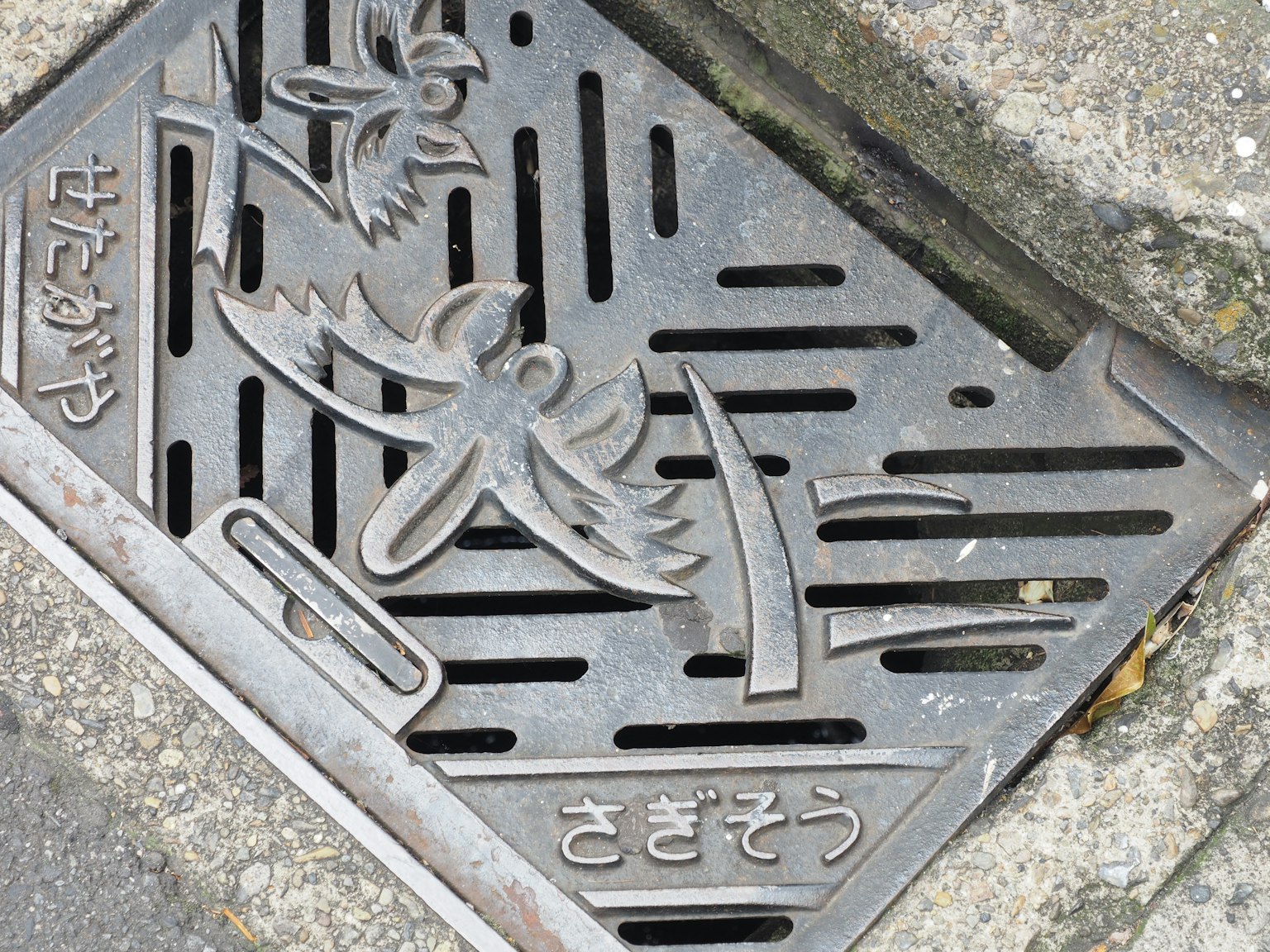 Metallene Schachtabdeckung mit einem Vogel und dekorativem Text