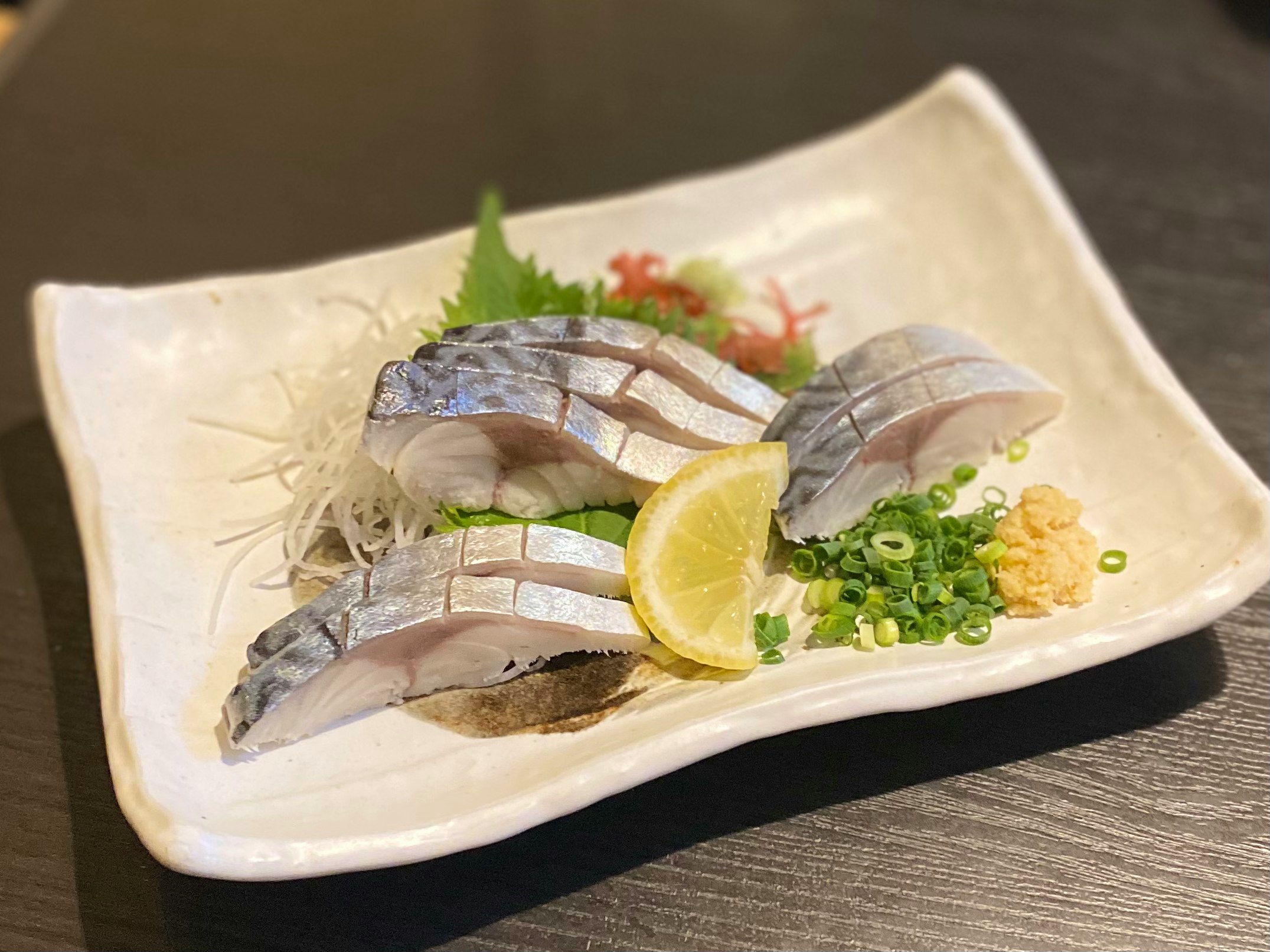 皿に盛られたサバの刺身とレモン添え