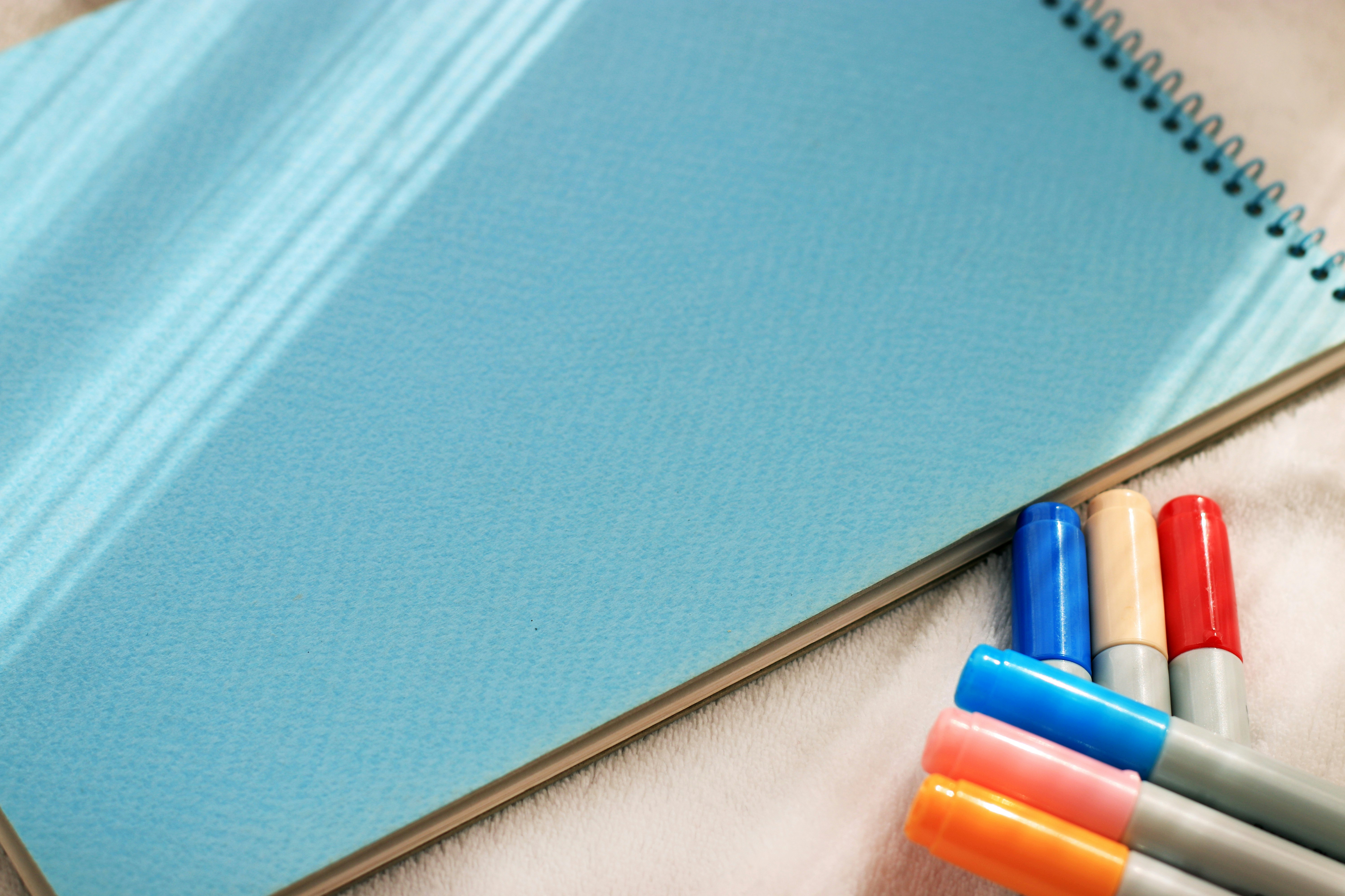 blue notebook with colorful pens on a desk