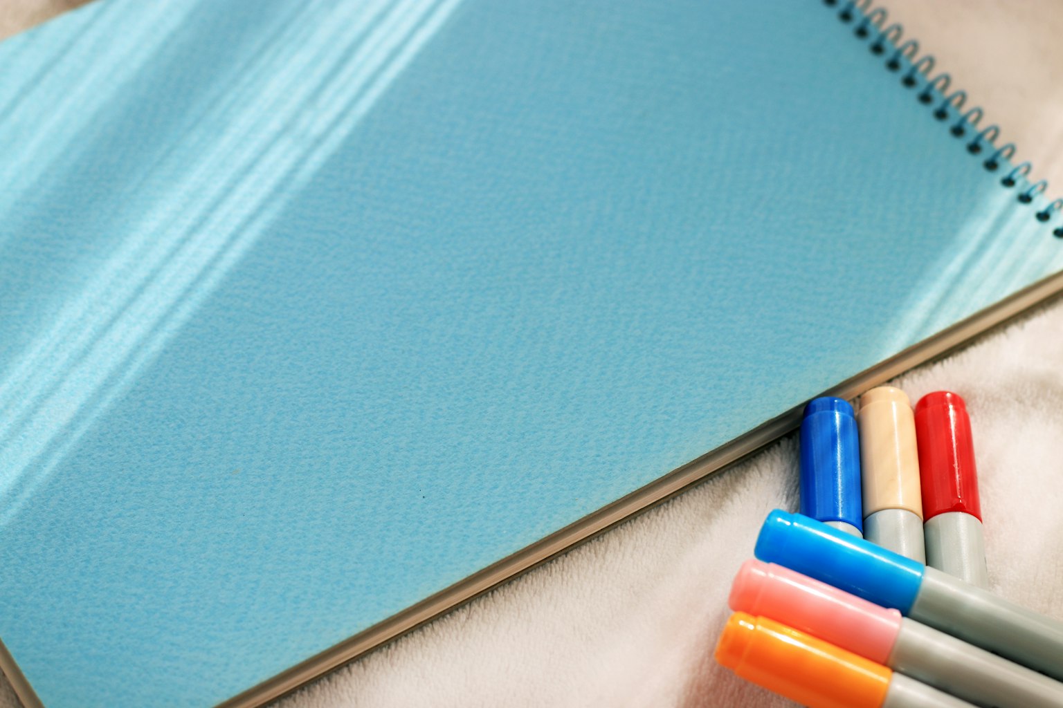 Bild eines blauen Notizbuchs mit bunten Markern daneben