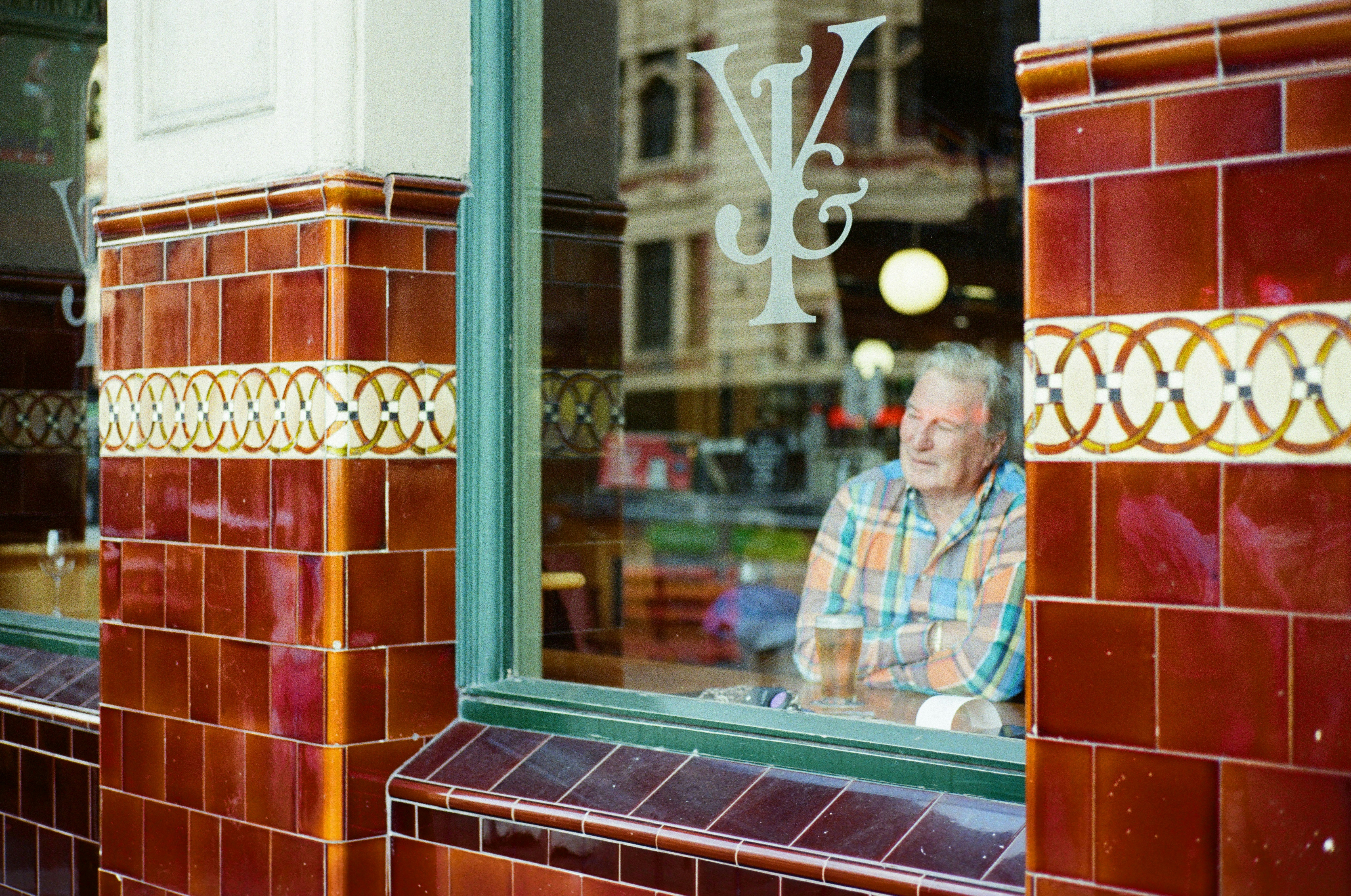 A man seen through a window between brick pillars in a cafe interior