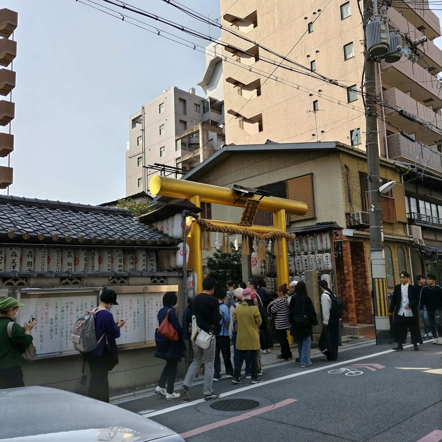 Vista di una strada con un cancello torii giallo e una folla di persone