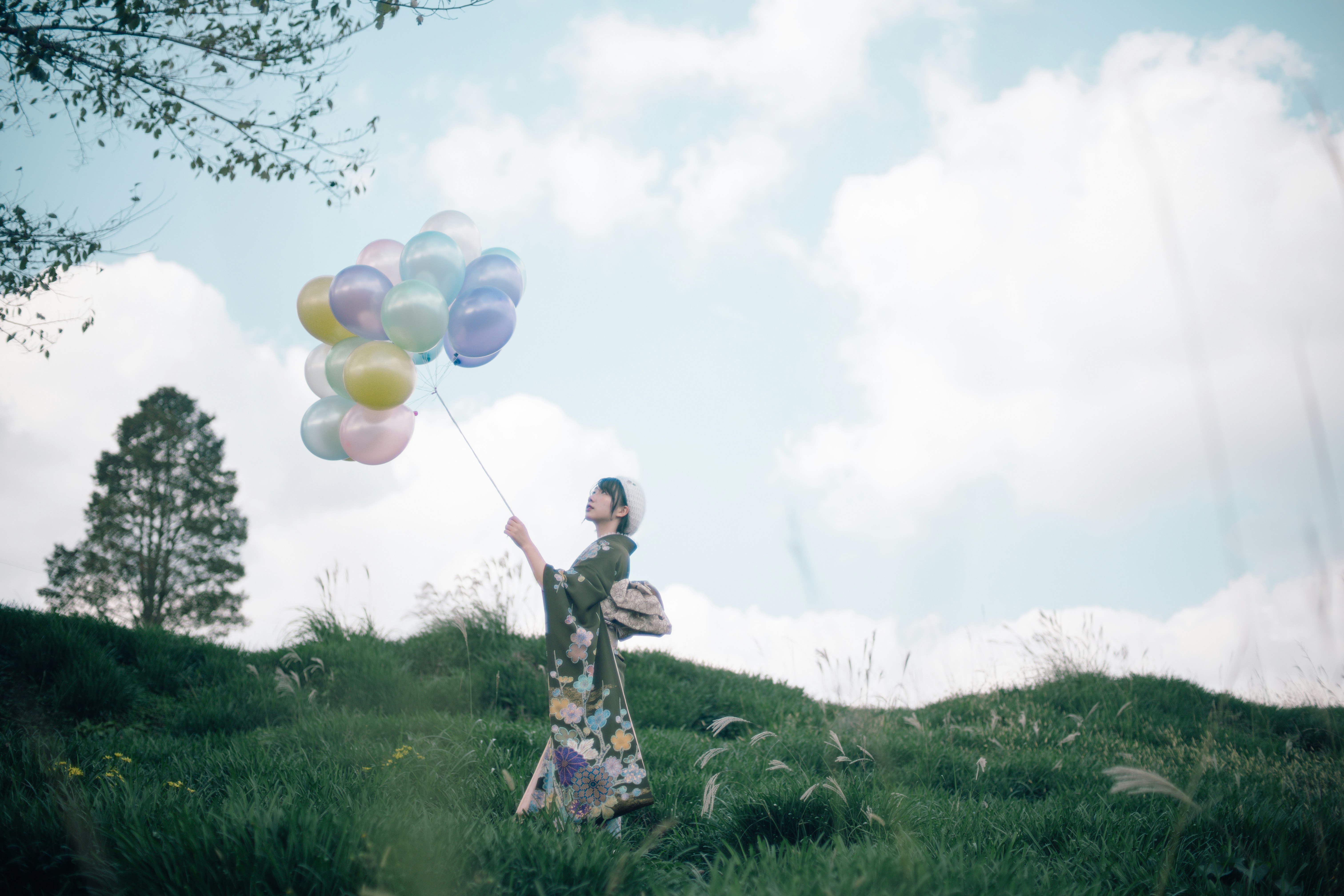 enfant souriant tenant des ballons dans un champ d’herbe