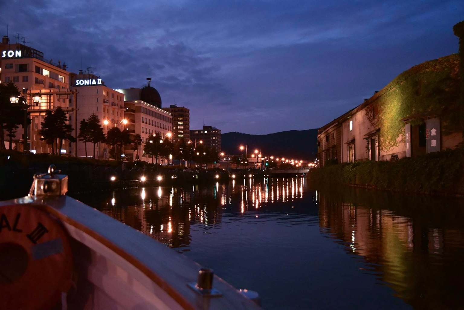Stadtlichter reflektieren sich nachts im ruhigen Wasser des Flusses
