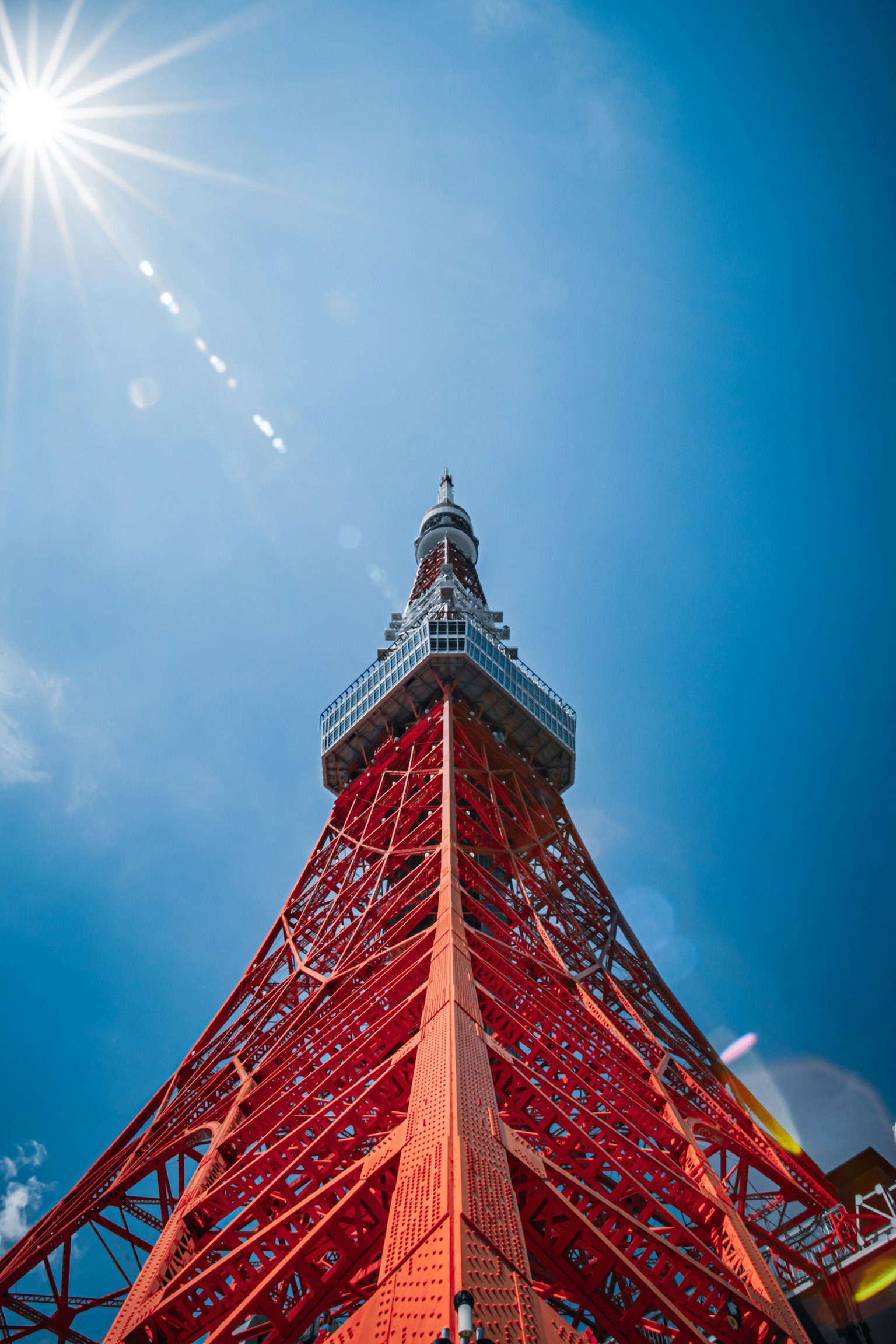Blick auf den Tokyo Tower von unten gegen einen klaren blauen Himmel und strahlende Sonne