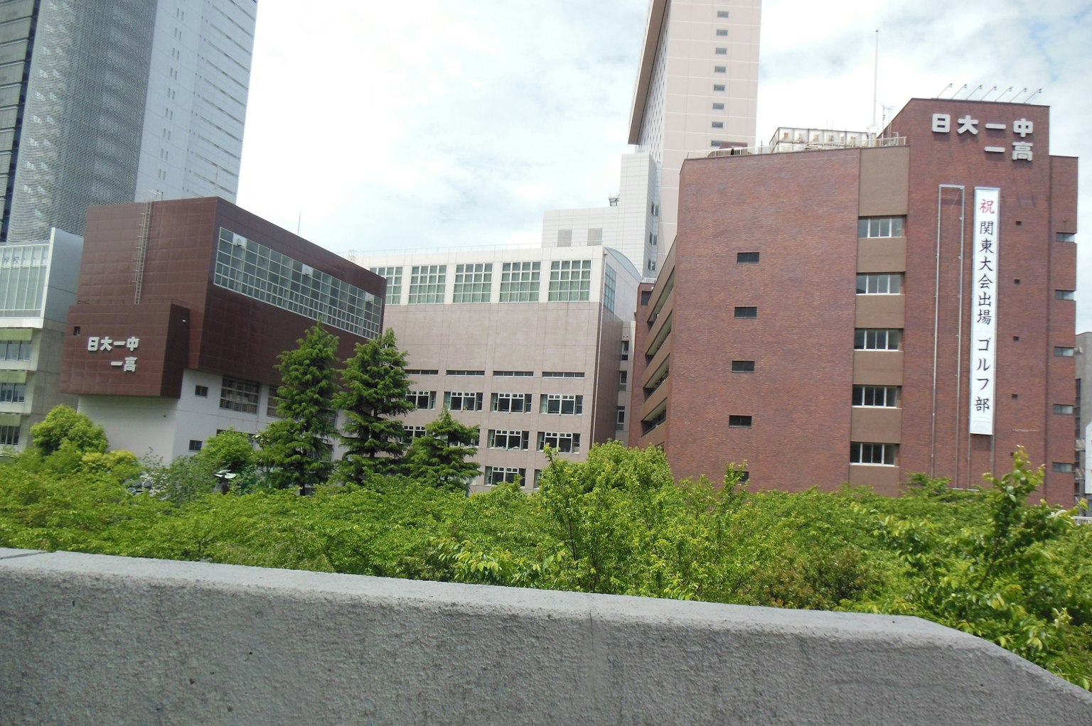 多座建築被綠樹環繞，背景中有摩天大樓的景觀