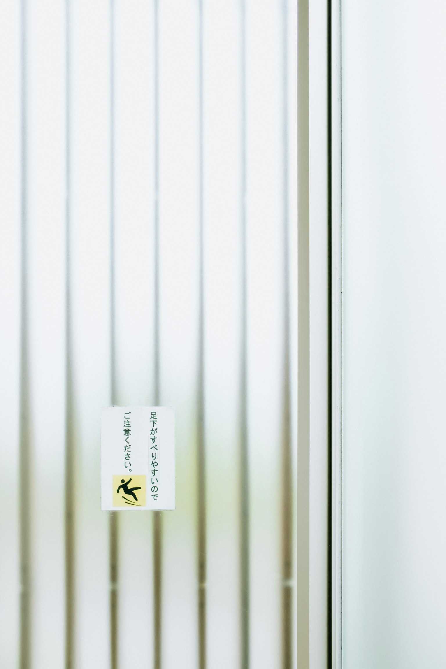 Teil einer Tür mit vertikalen Streifen vor einem weißen Hintergrund und einem gelben Etikett