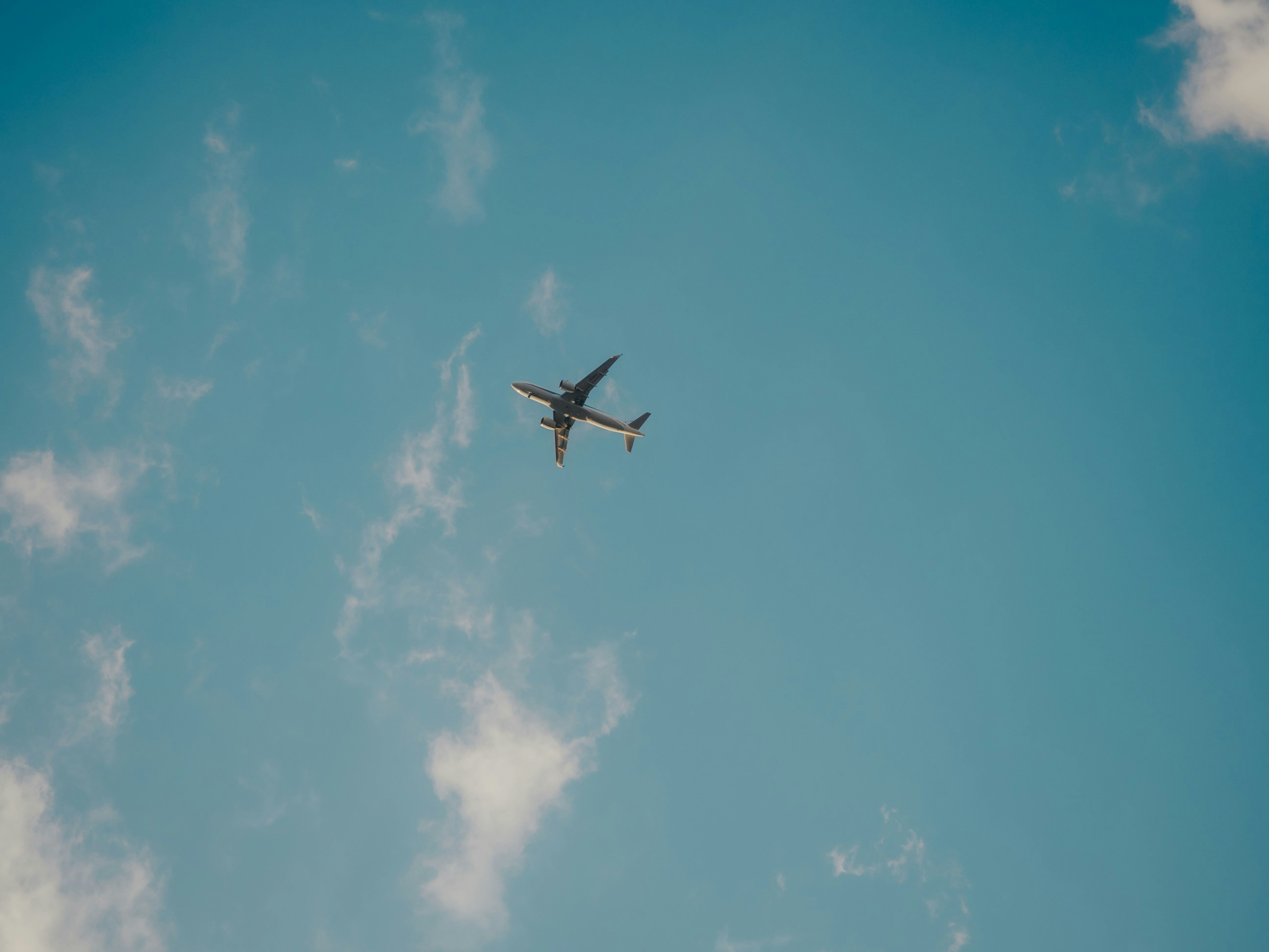 青空に飛ぶ旅客機のシルエット