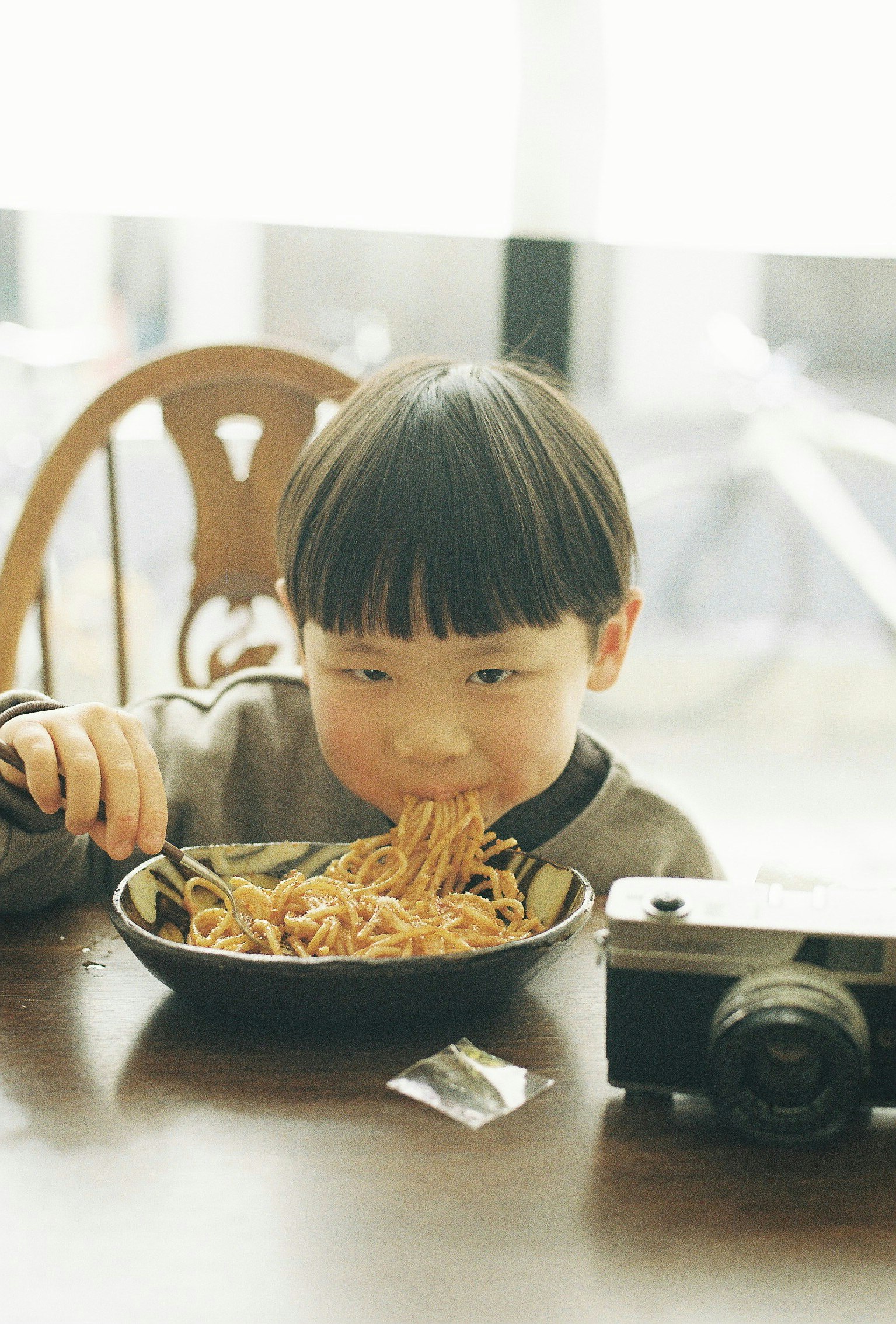 niño sonriente comiendo fideos en la mesa
