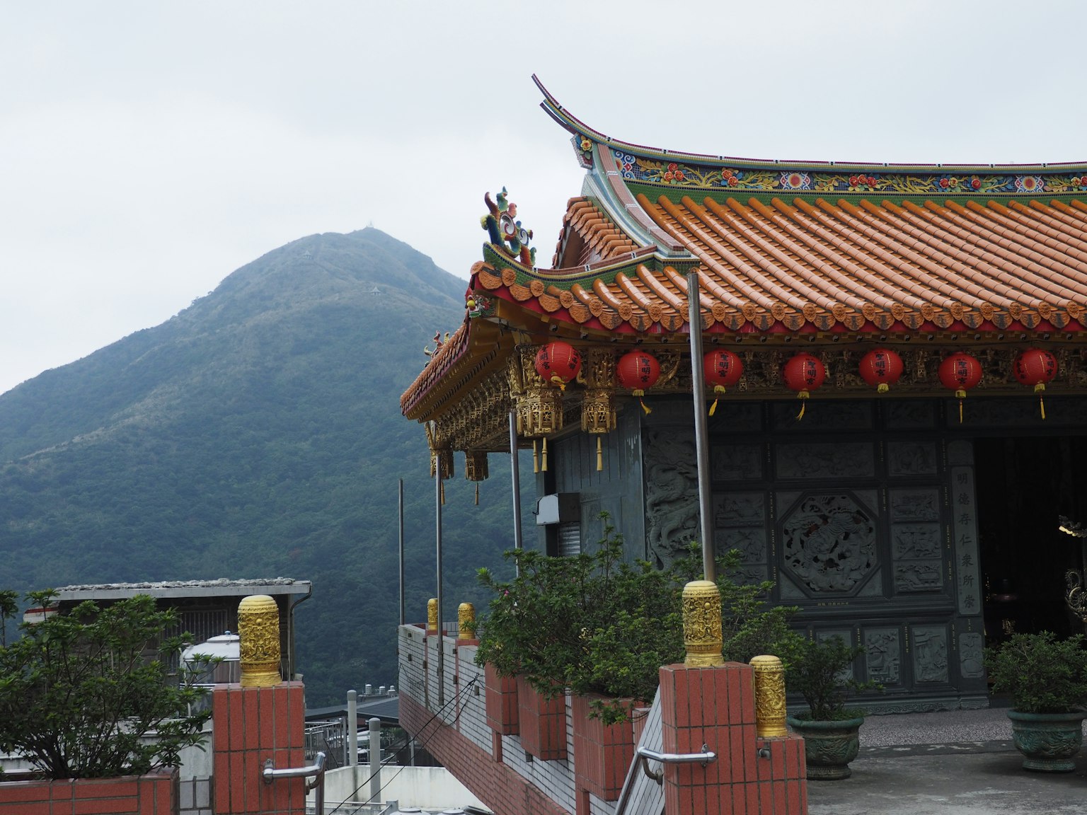 风景如画的寺庙，华丽的屋顶和红色灯笼，背景是山脉