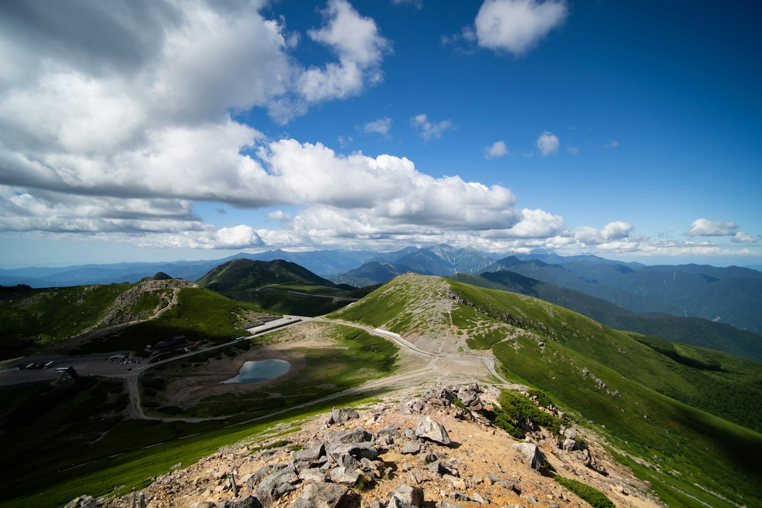 Vista panoramica di montagne verdi sotto un cielo blu con nuvole bianche