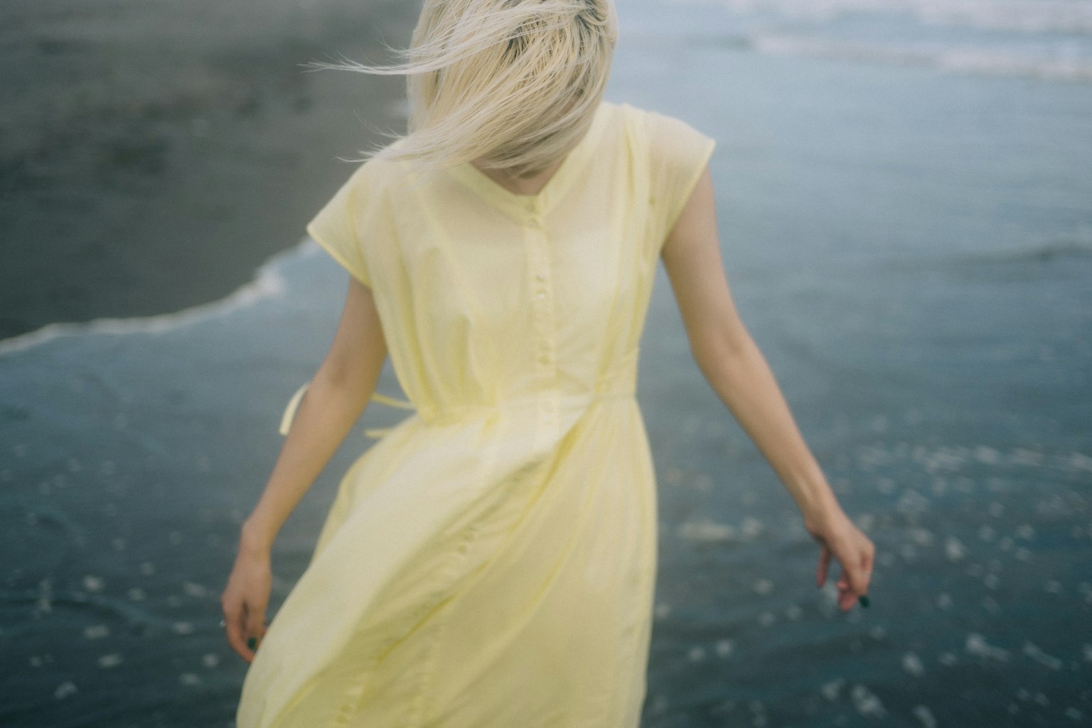海邊穿著飄逸黃色裙子的女性