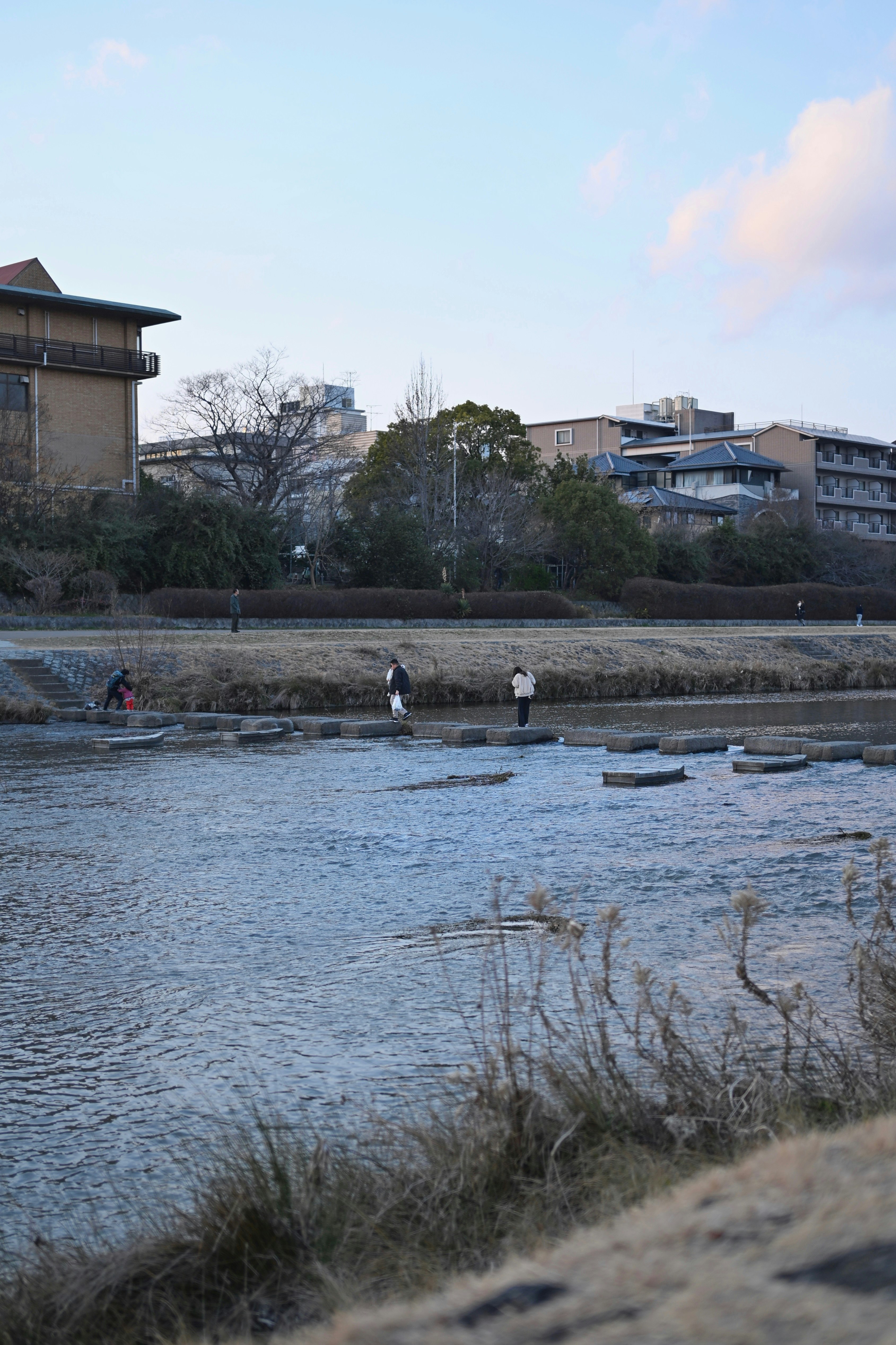 personas paseando junto al río Kamo y el agua al frente