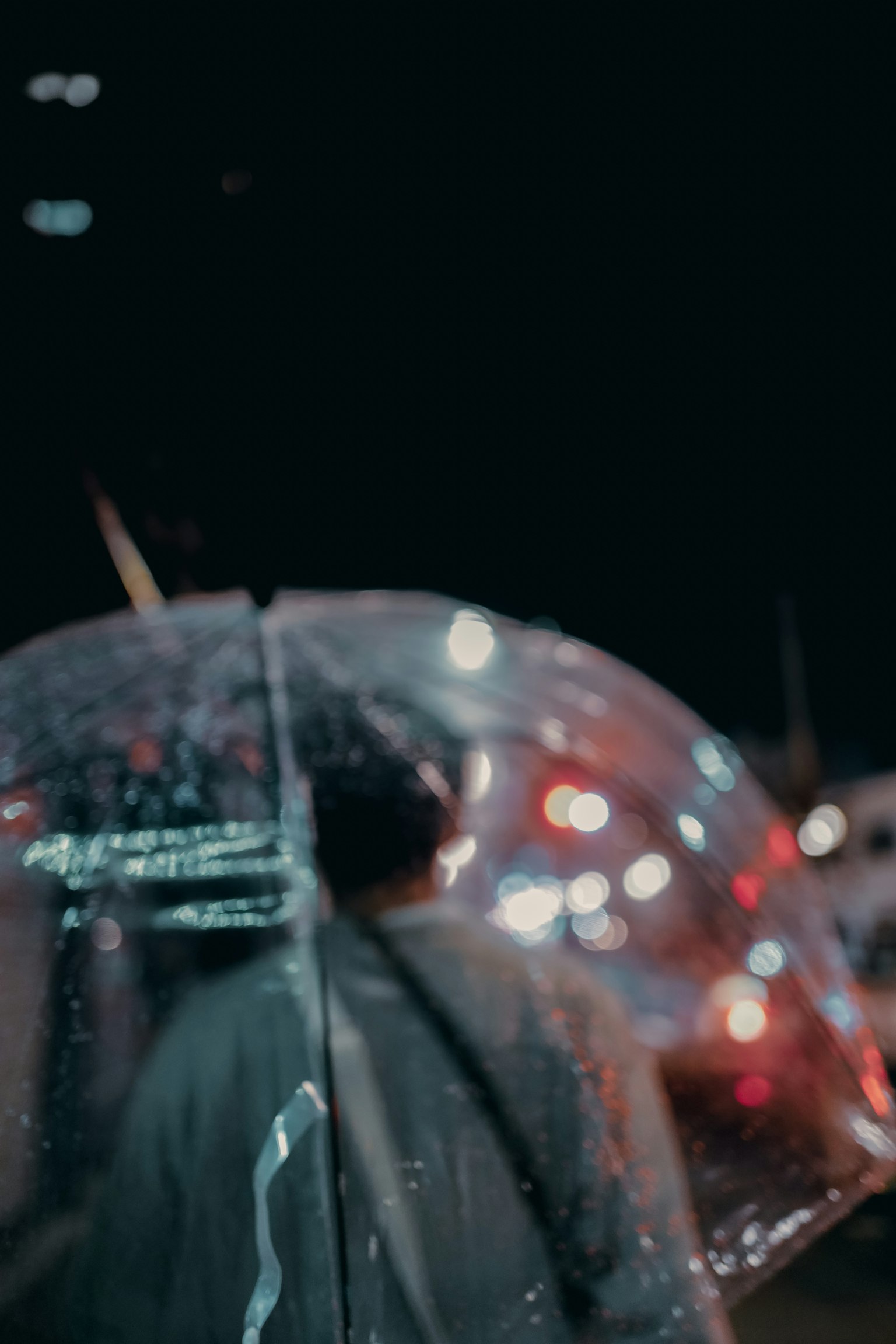 一個人拿著透明傘在夜間走路