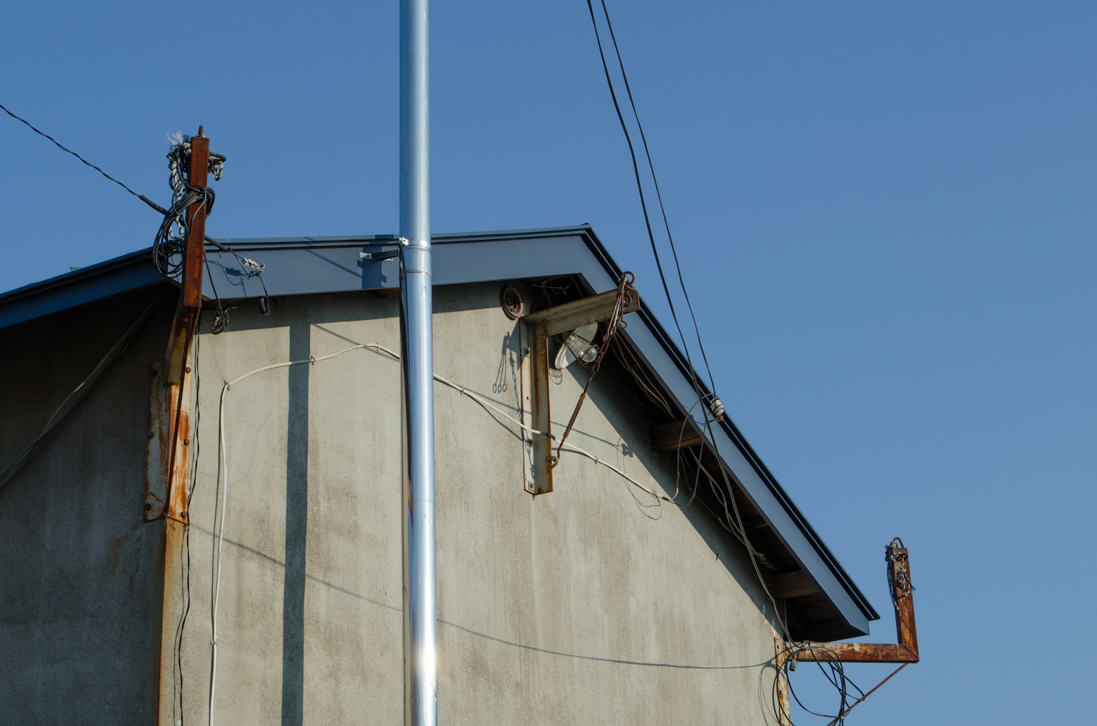 Vista del techo de un edificio antiguo con cables eléctricos bajo un cielo azul claro