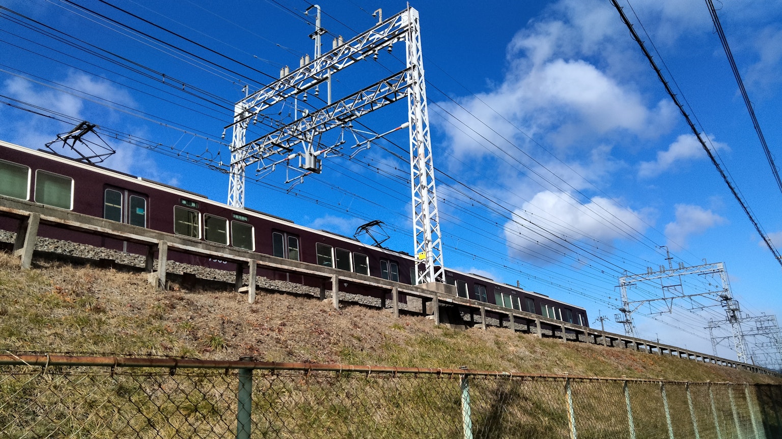 Train running under blue sky with overhead lines